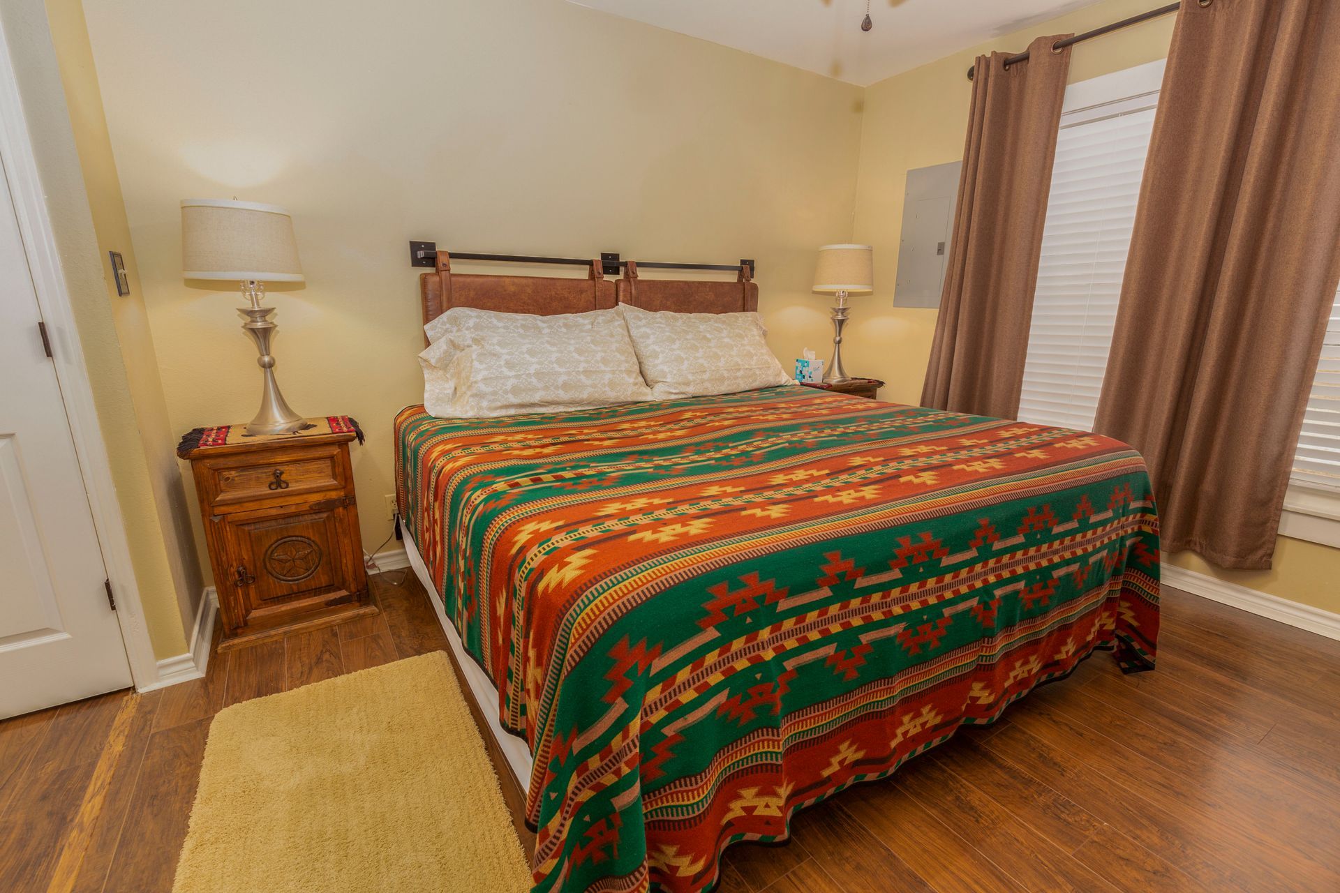 A bedroom with a king size bed , nightstand , lamp and rug.