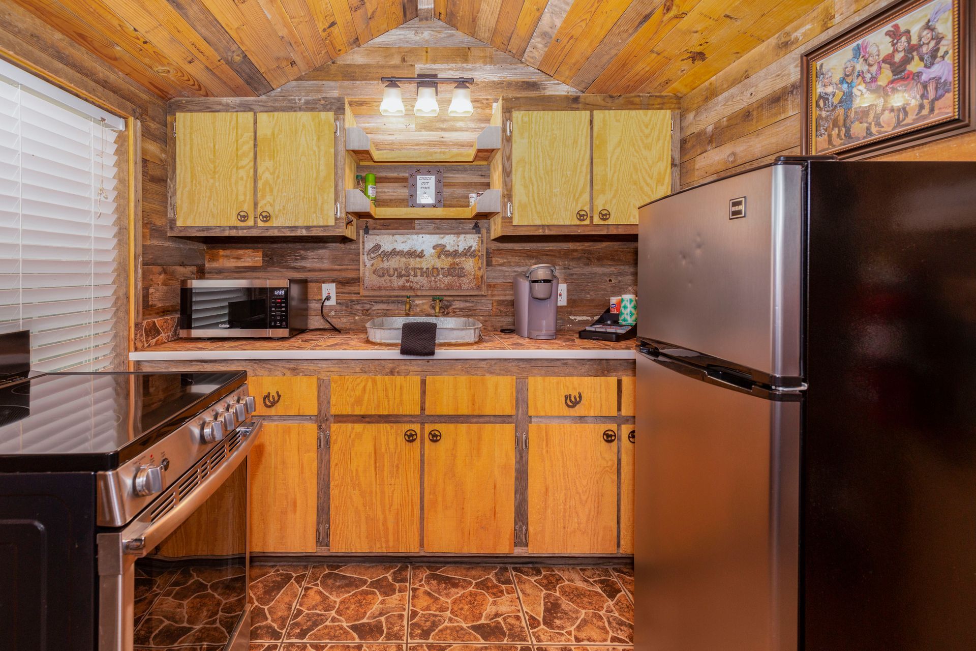 A kitchen in a log cabin with stainless steel appliances and wooden cabinets.
