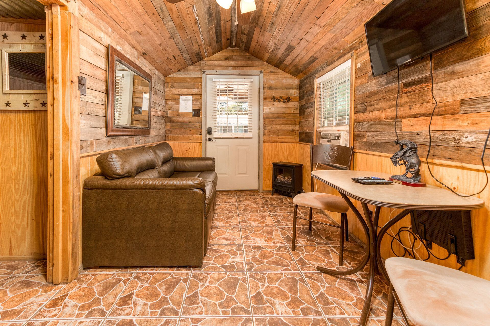 A living room in a log cabin with a couch , table and television.