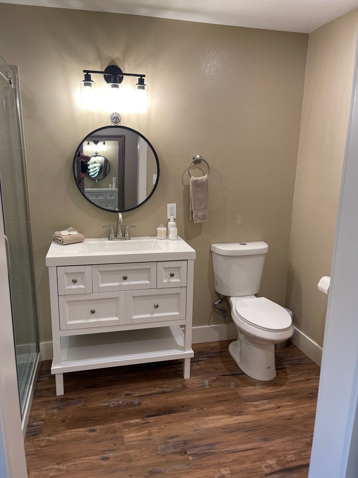A bathroom with a toilet , sink and mirror.