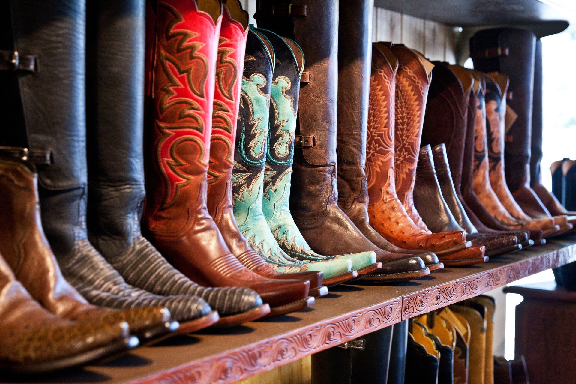 A row of cowboy boots are lined up on a shelf.