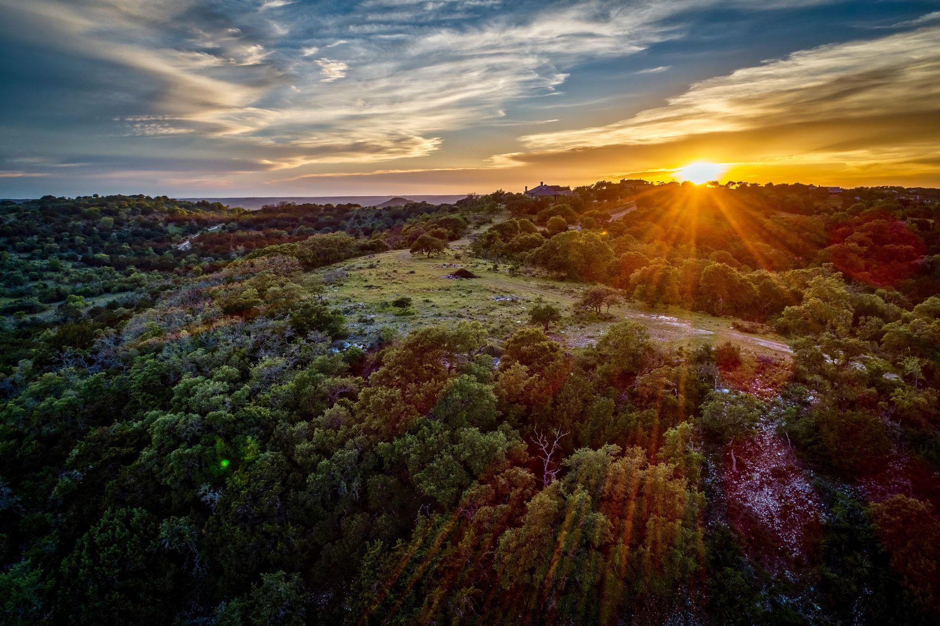 An aerial view of a sunset over a lush green forest.