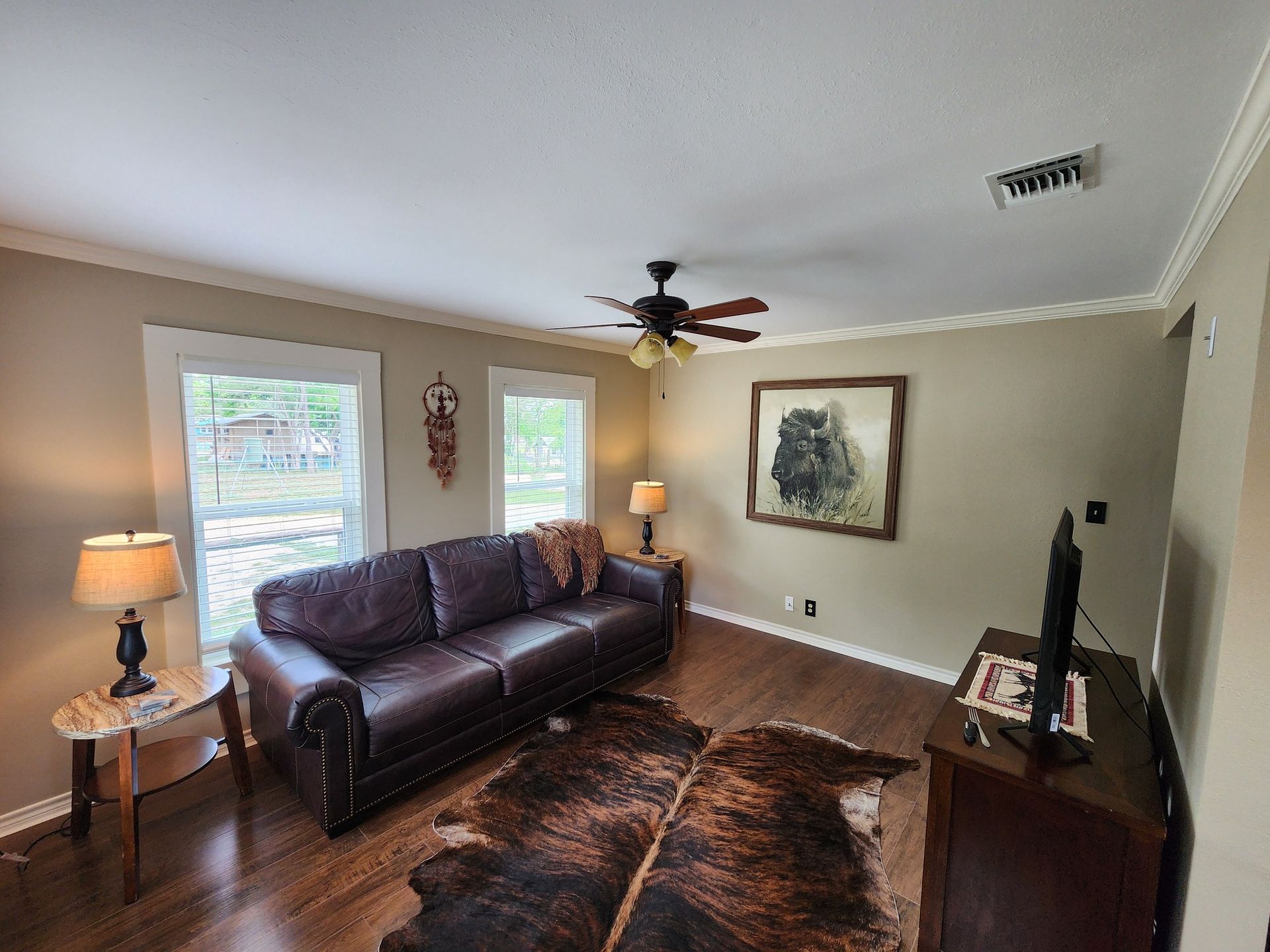 A living room with a couch , rug , television and ceiling fan.