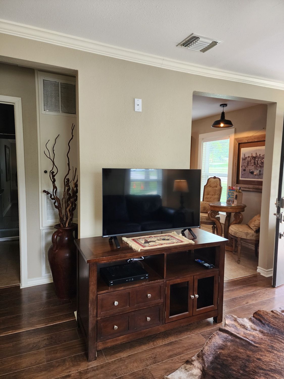 A living room with a flat screen tv on a wooden entertainment center.