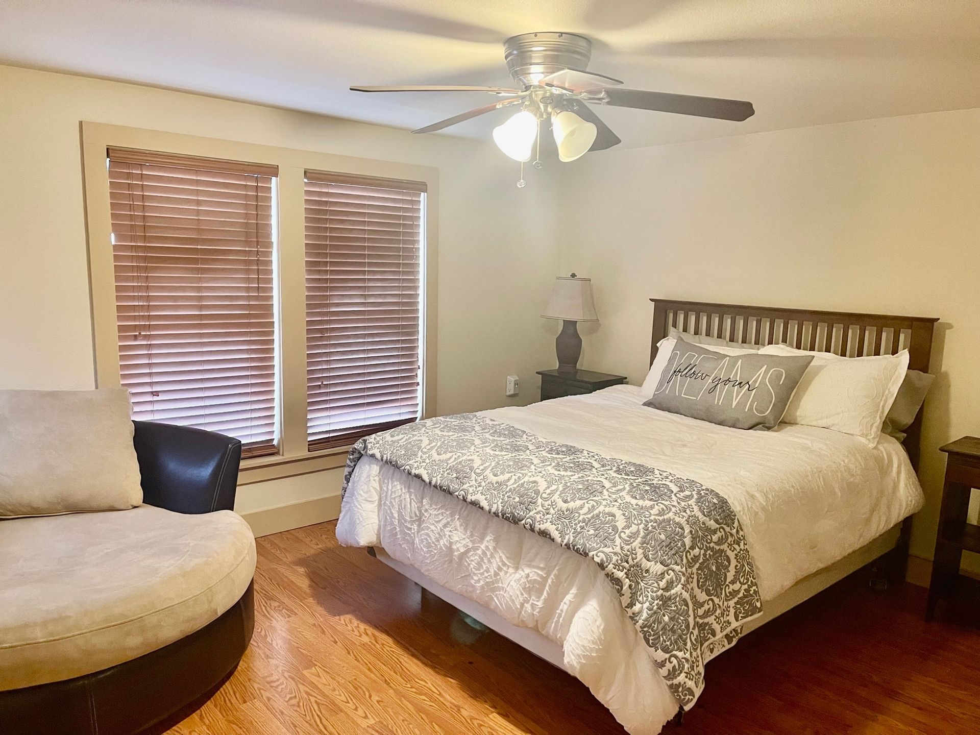A bedroom with a bed , chair and ceiling fan.