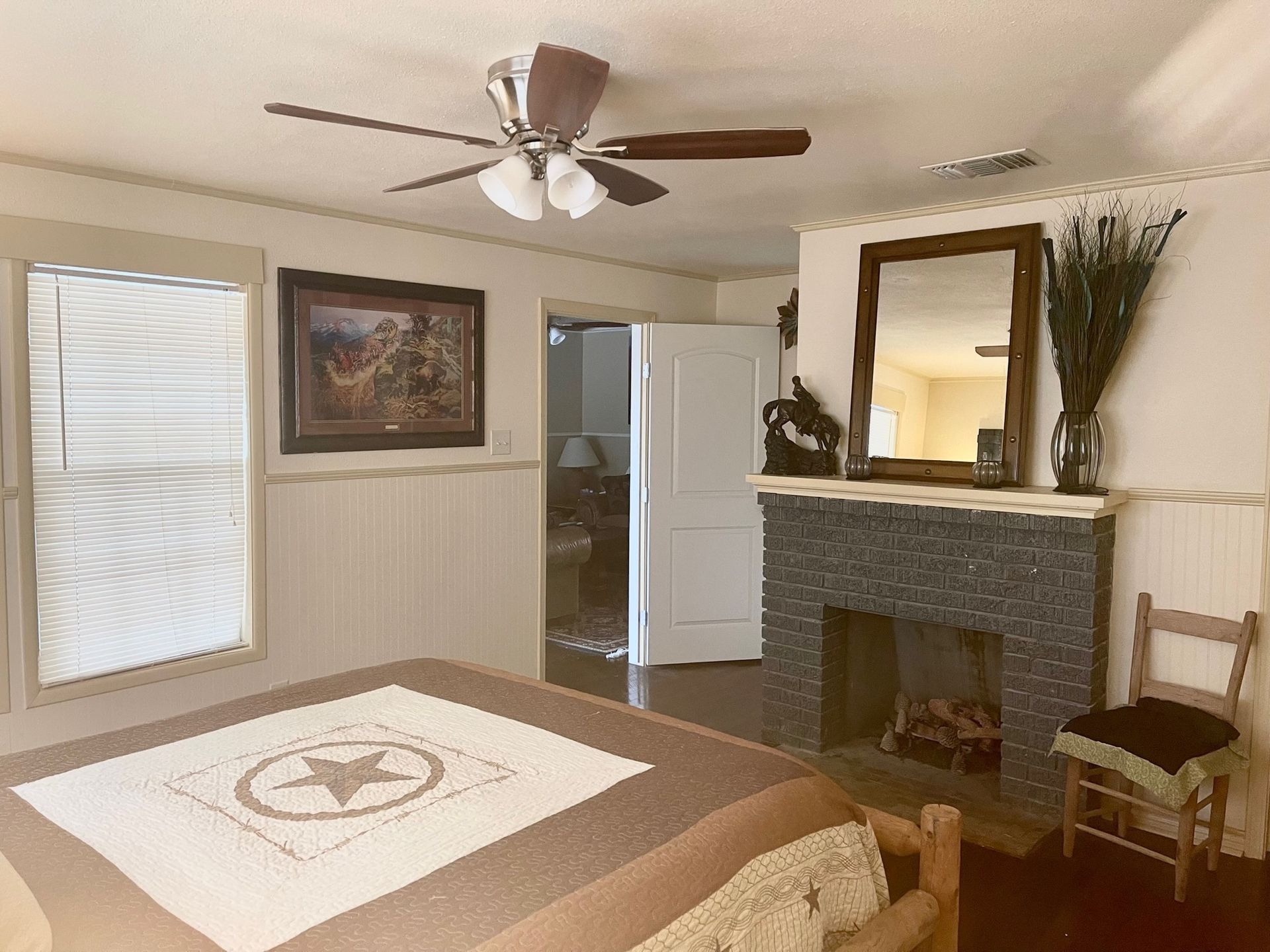 A bedroom with a fireplace and a ceiling fan