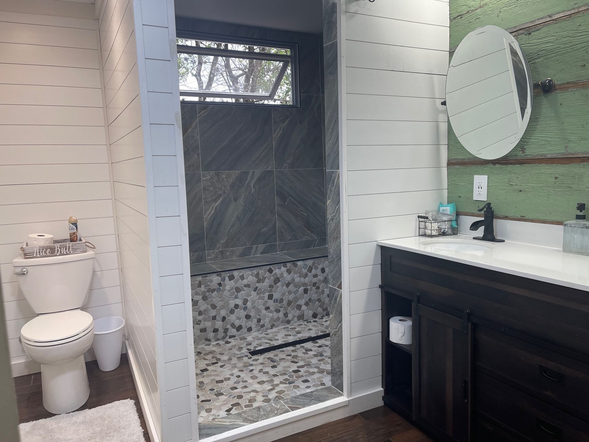 A bathroom with a toilet , sink , mirror and walk in shower.