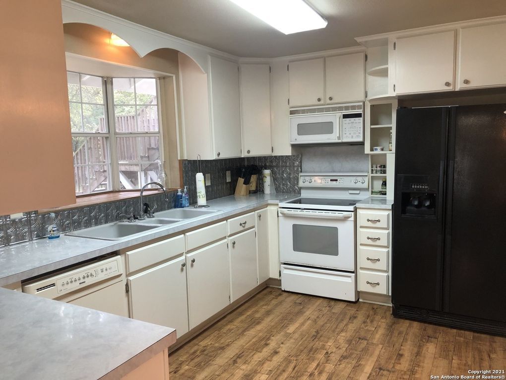 A kitchen with white cabinets and a black refrigerator