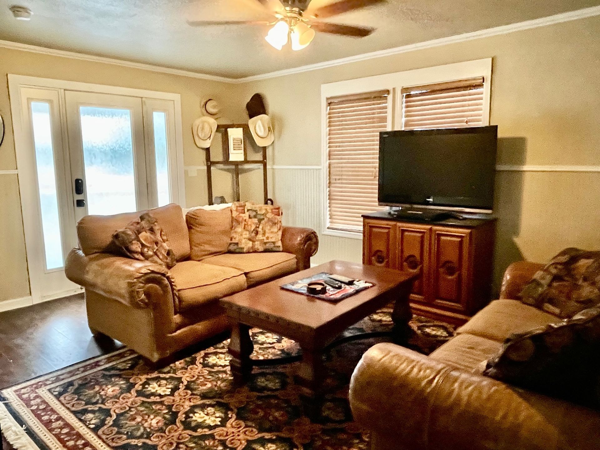 A living room with a couch , chair , coffee table and television.