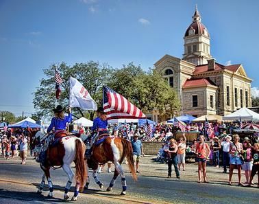 A group of people are riding horses down a street in a parade.