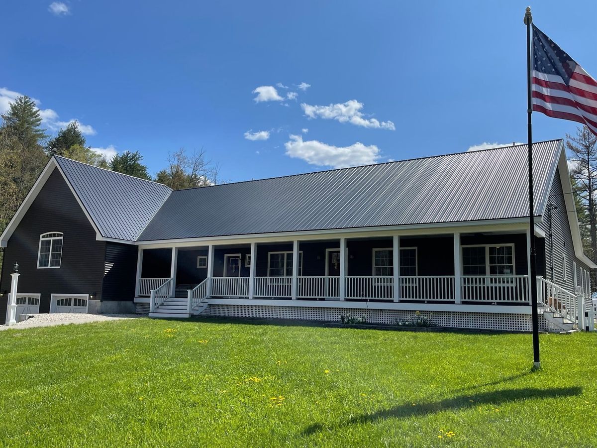 A large house with a porch and an american flag in front of it.