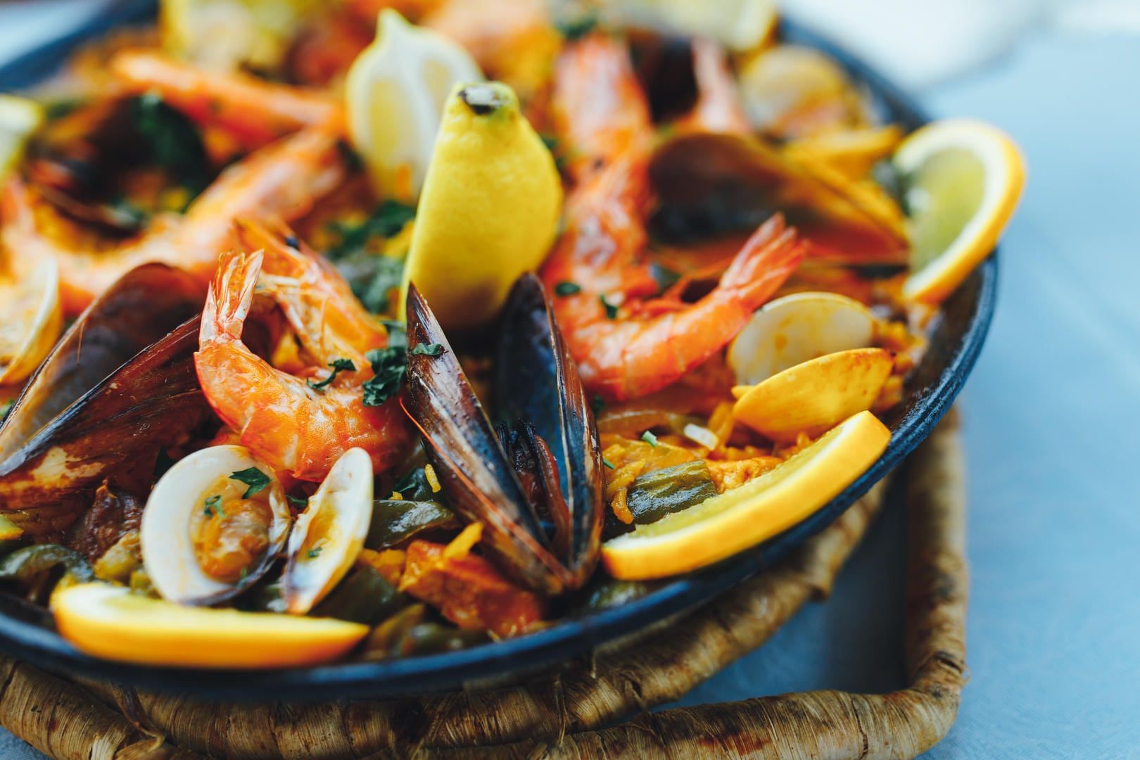 A close up of a paella with shrimp , mussels , and lemon slices.