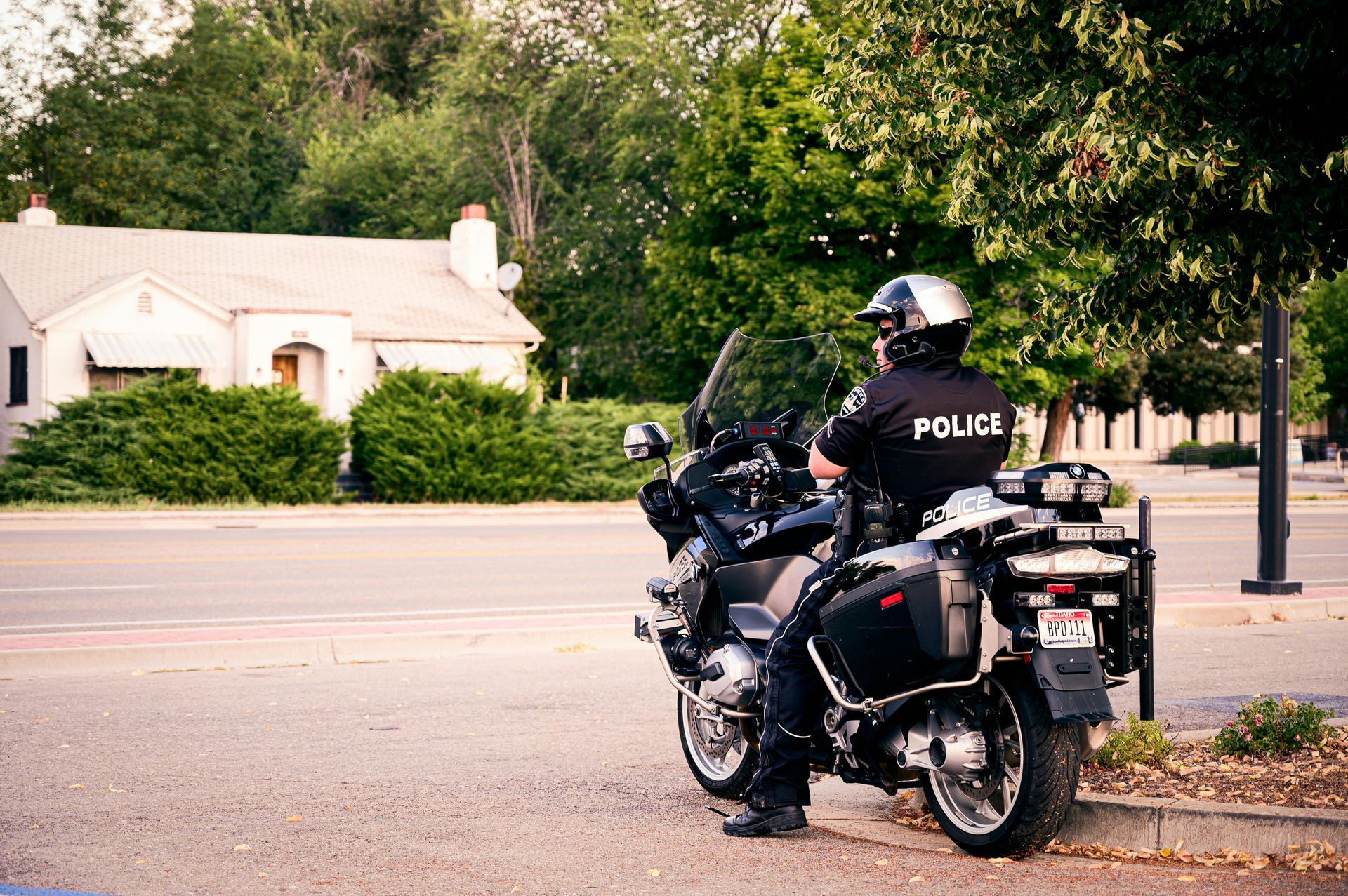 A police officer is riding a motorcycle on the side of the road.