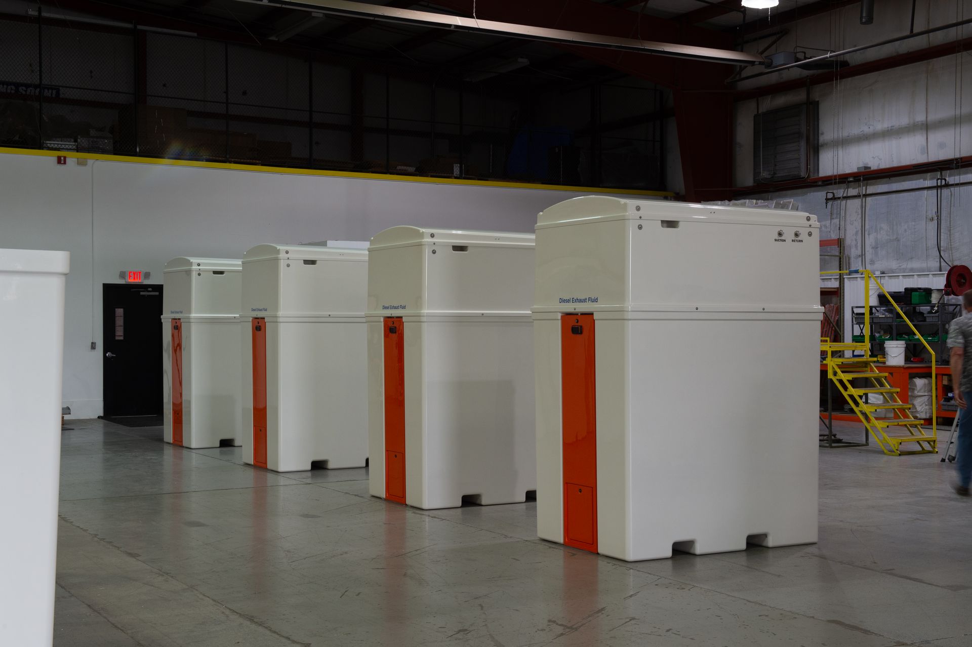 Five white, rectangular BENECOR machines with orange stripes, lined up in a warehouse.