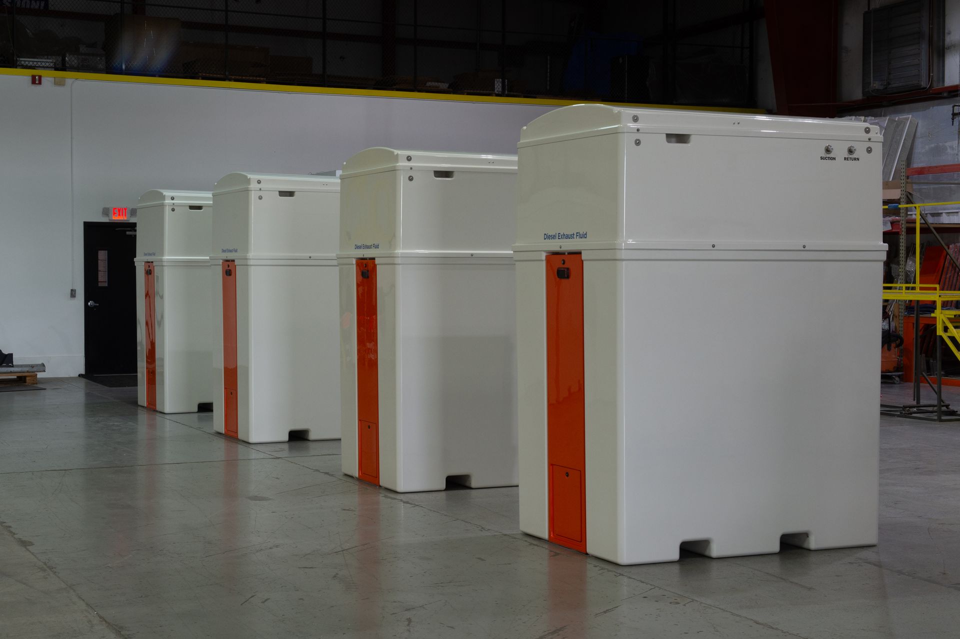 Five large, white industrial machines with orange accents lined up in a factory setting.