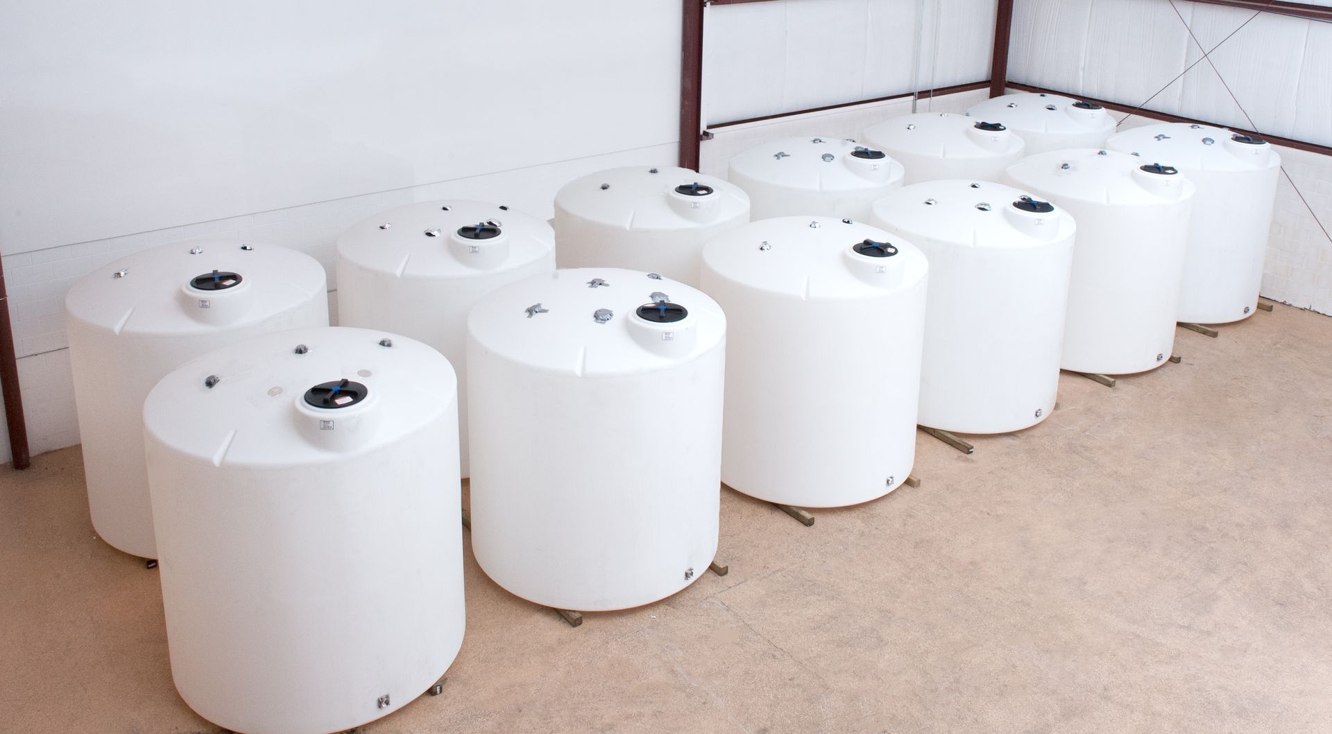 White cylindrical storage tanks lined up in a room.