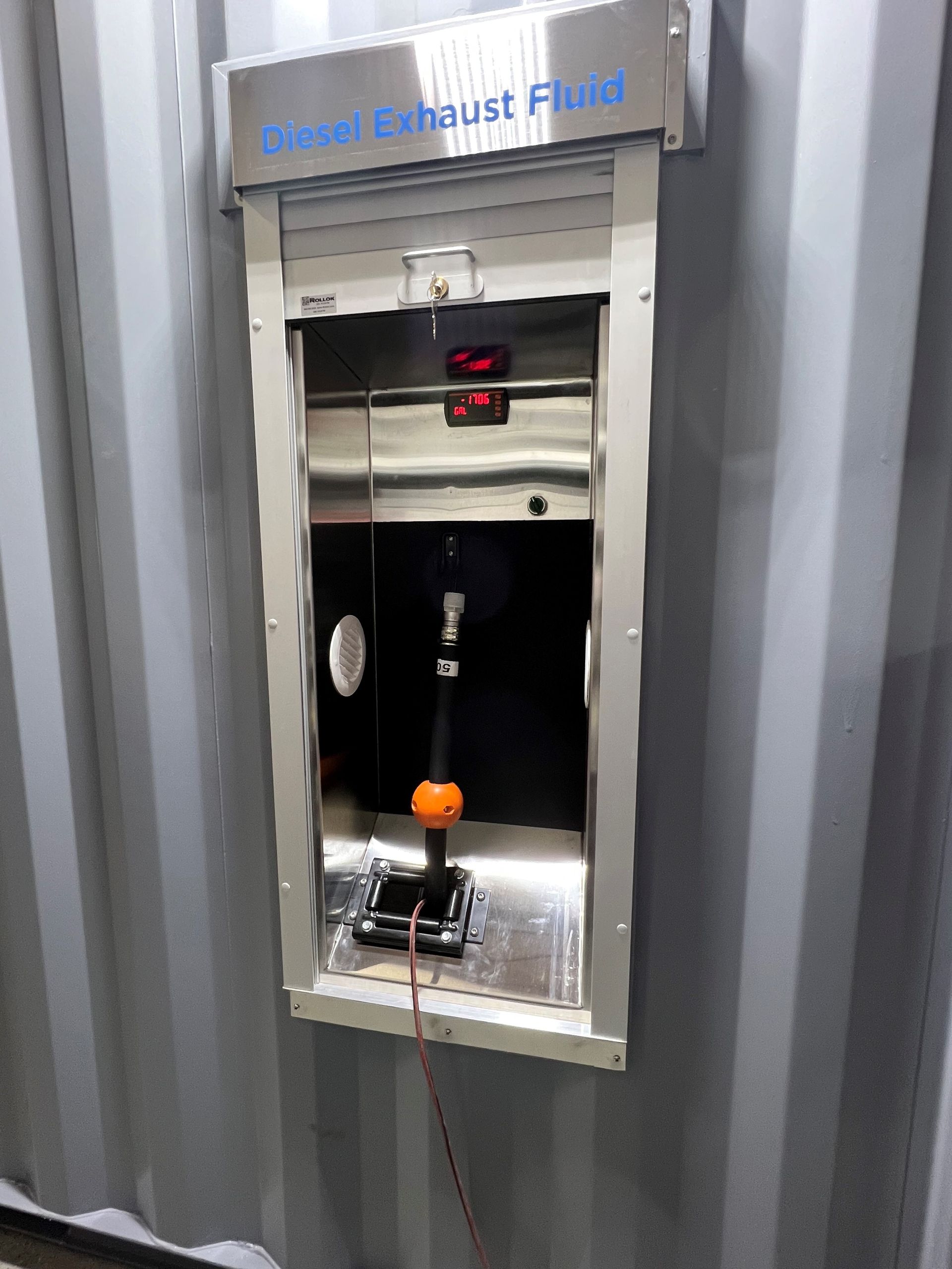 Diesel Exhaust Fluid dispenser, stainless steel enclosure on gray container.