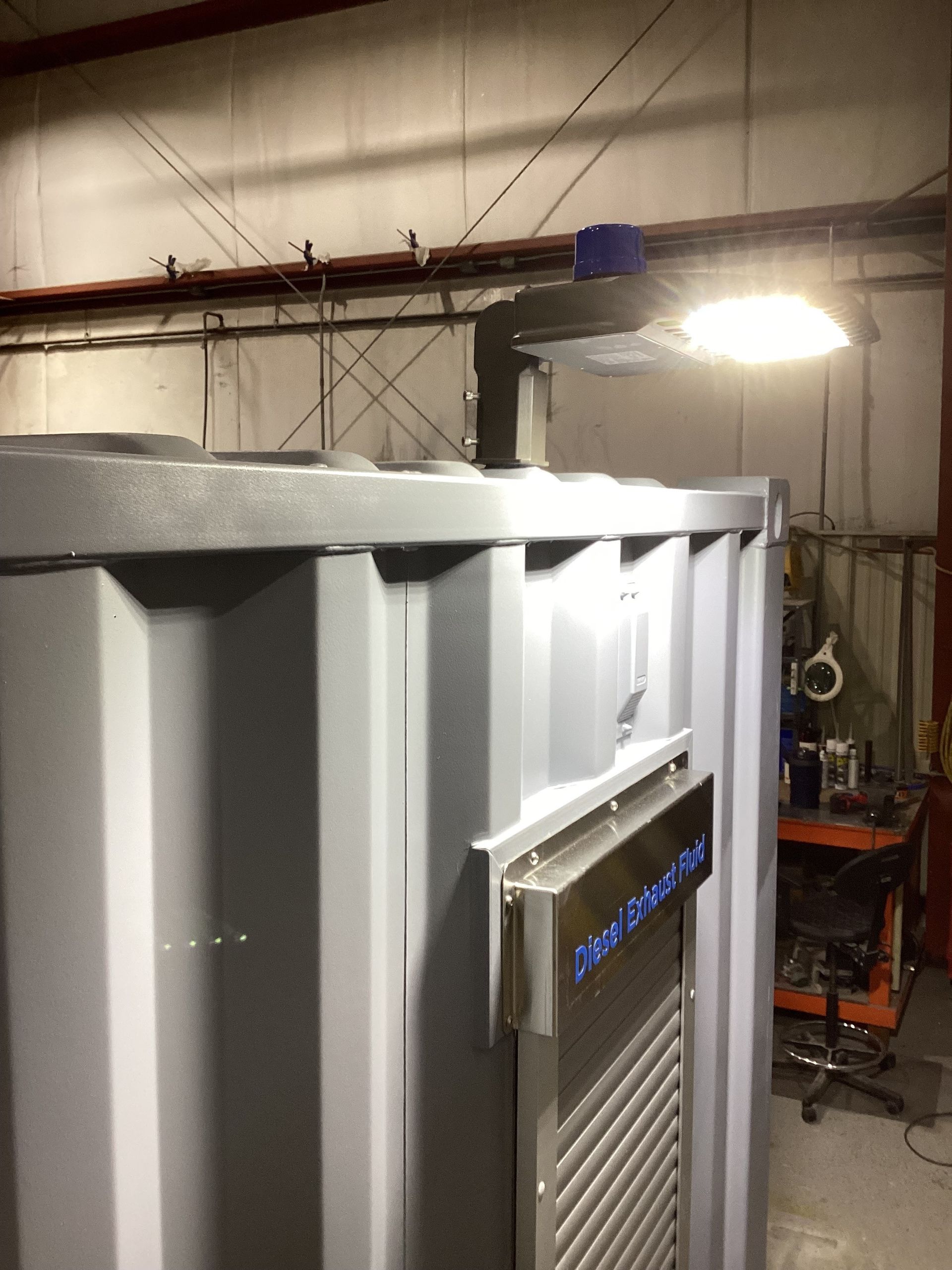 Gray metal container with a vent and overhead lighting in an industrial setting.