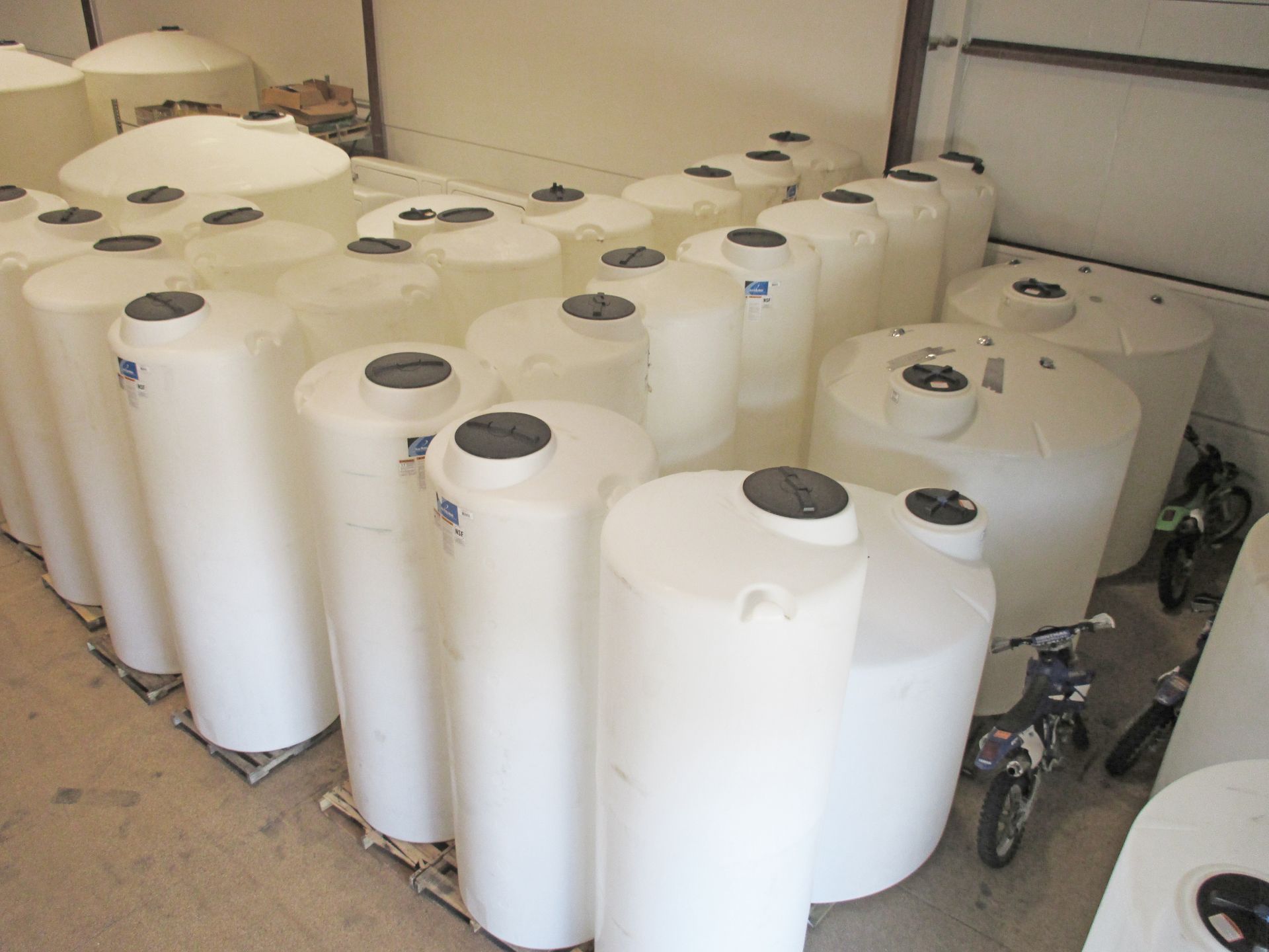 White cylindrical storage tanks in an indoor setting, likely a warehouse.