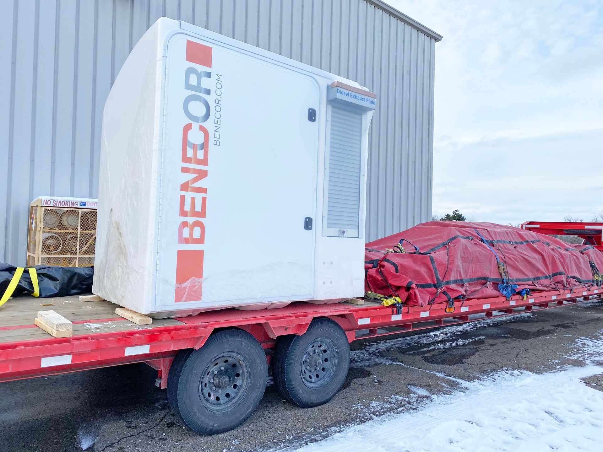 A large white Benecor generator on a red trailer, ready for transport.