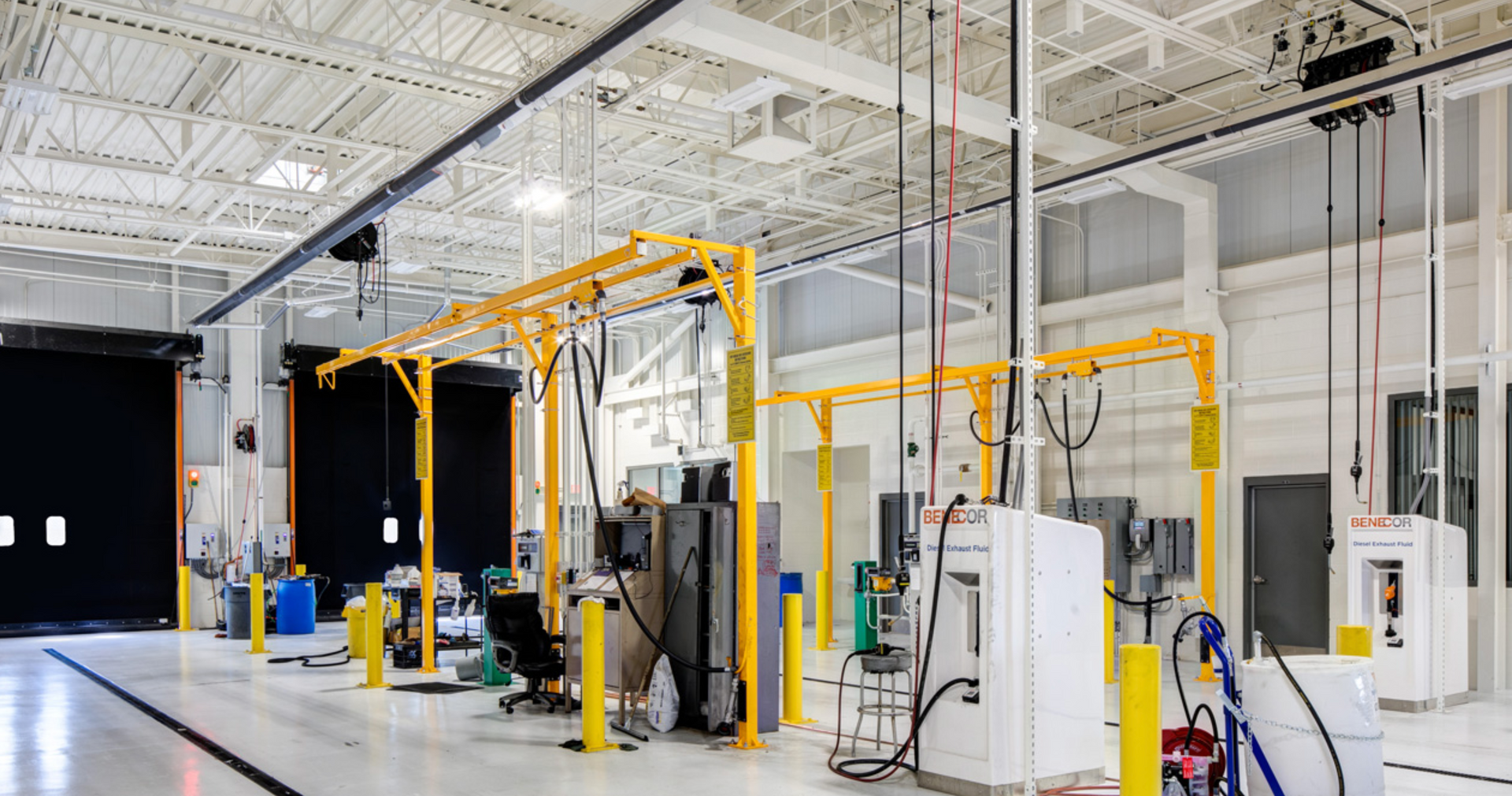 Yellow overhead crane system in a white factory setting with equipment and machinery.