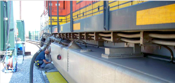 A person refueling a train with a black hose. The train is yellow, orange, and gray.