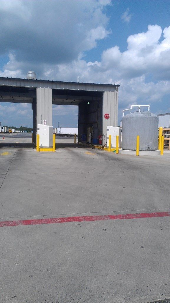 Entrance to industrial facility with overhead shelter, concrete, and equipment.