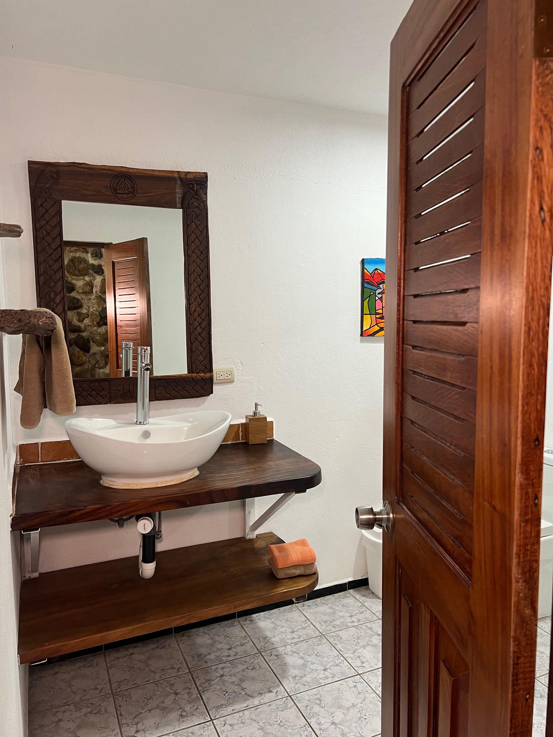 A bathroom with a sink , mirror and a wooden door.