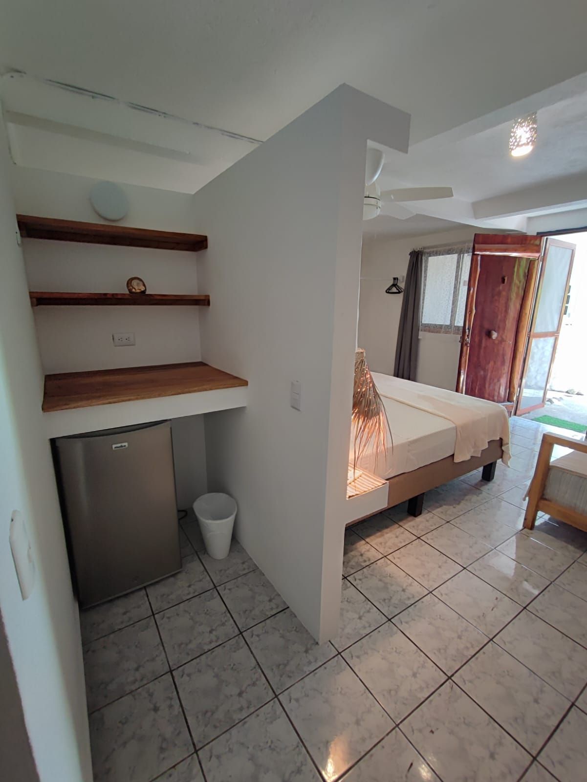 A bedroom with a king size bed and a small refrigerator