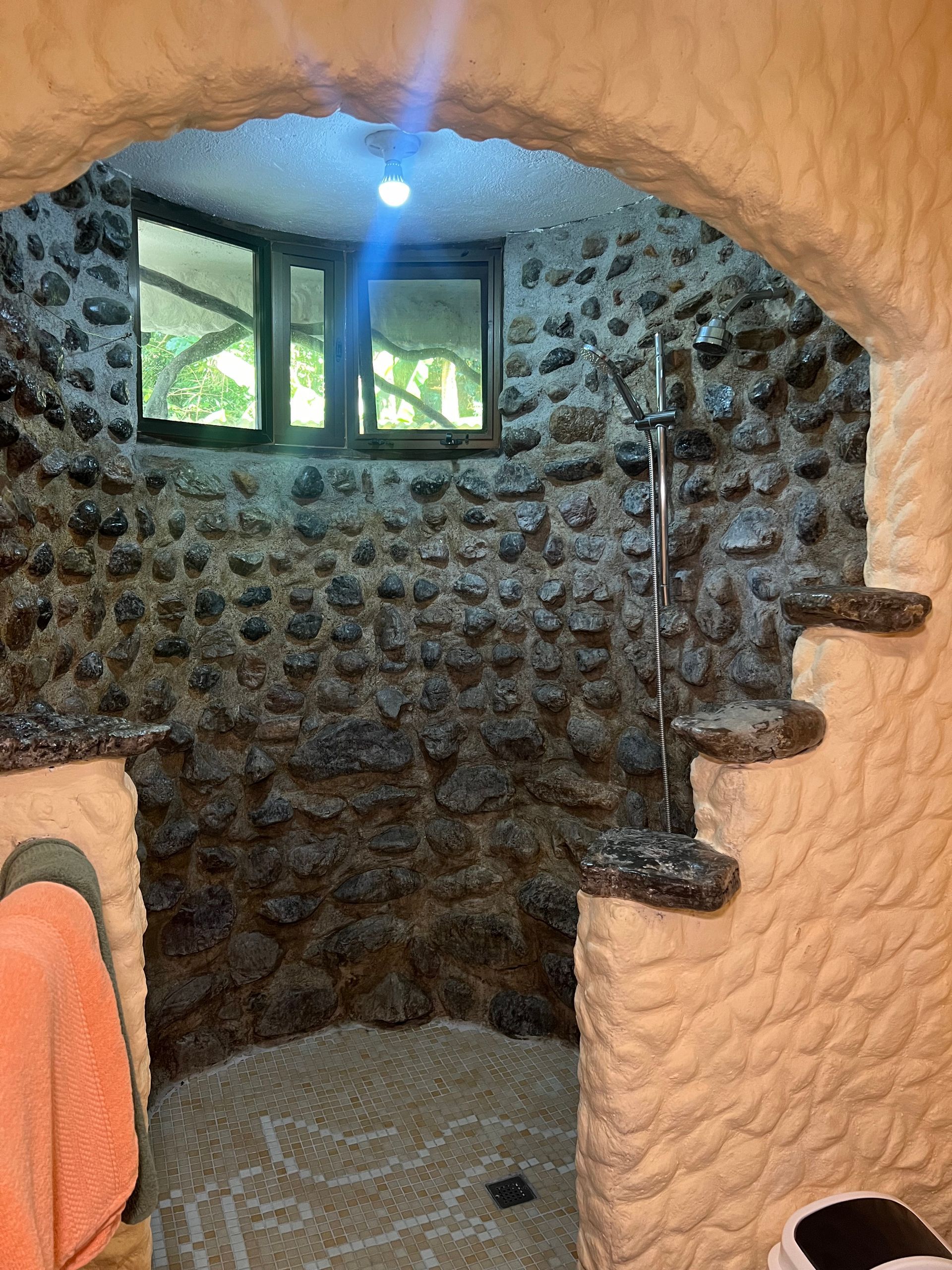 A bathroom with a stone wall and a shower.