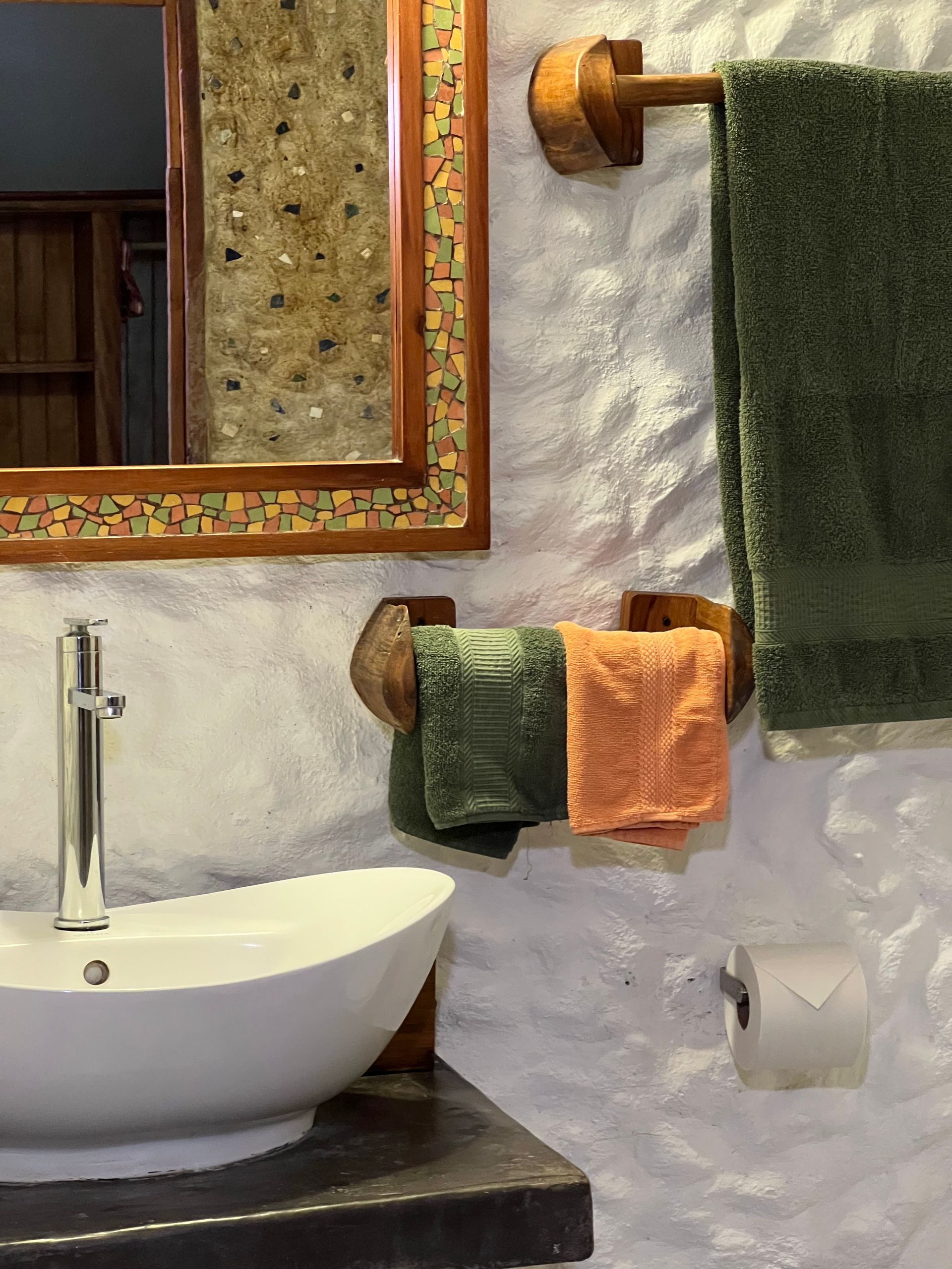 A bathroom with a sink , mirror , and towels hanging on the wall.