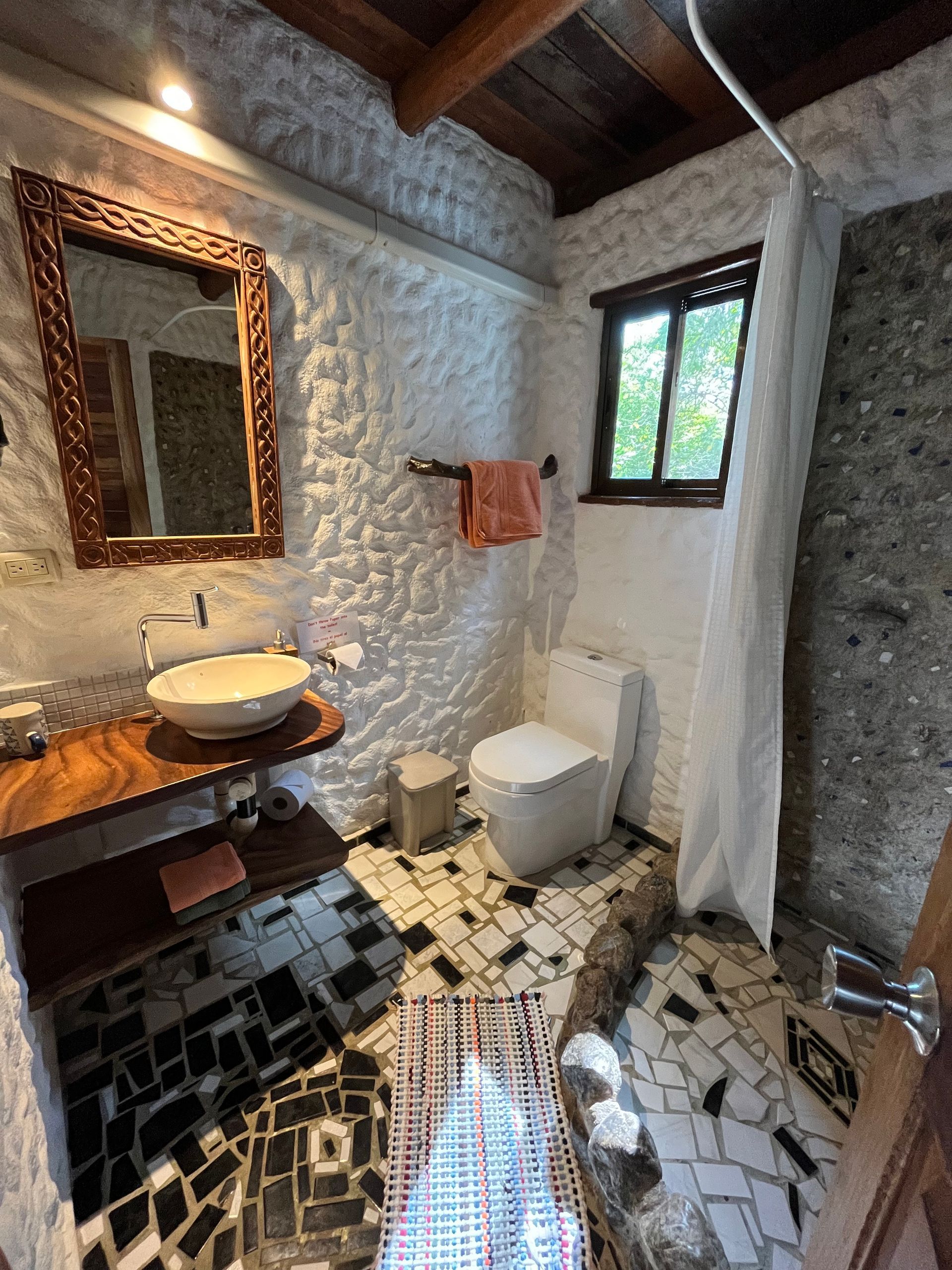A bathroom with a toilet , sink and mirror.