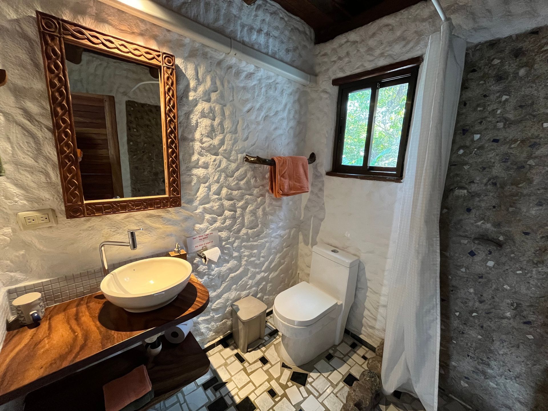 A bathroom with a sink , toilet , mirror and window.