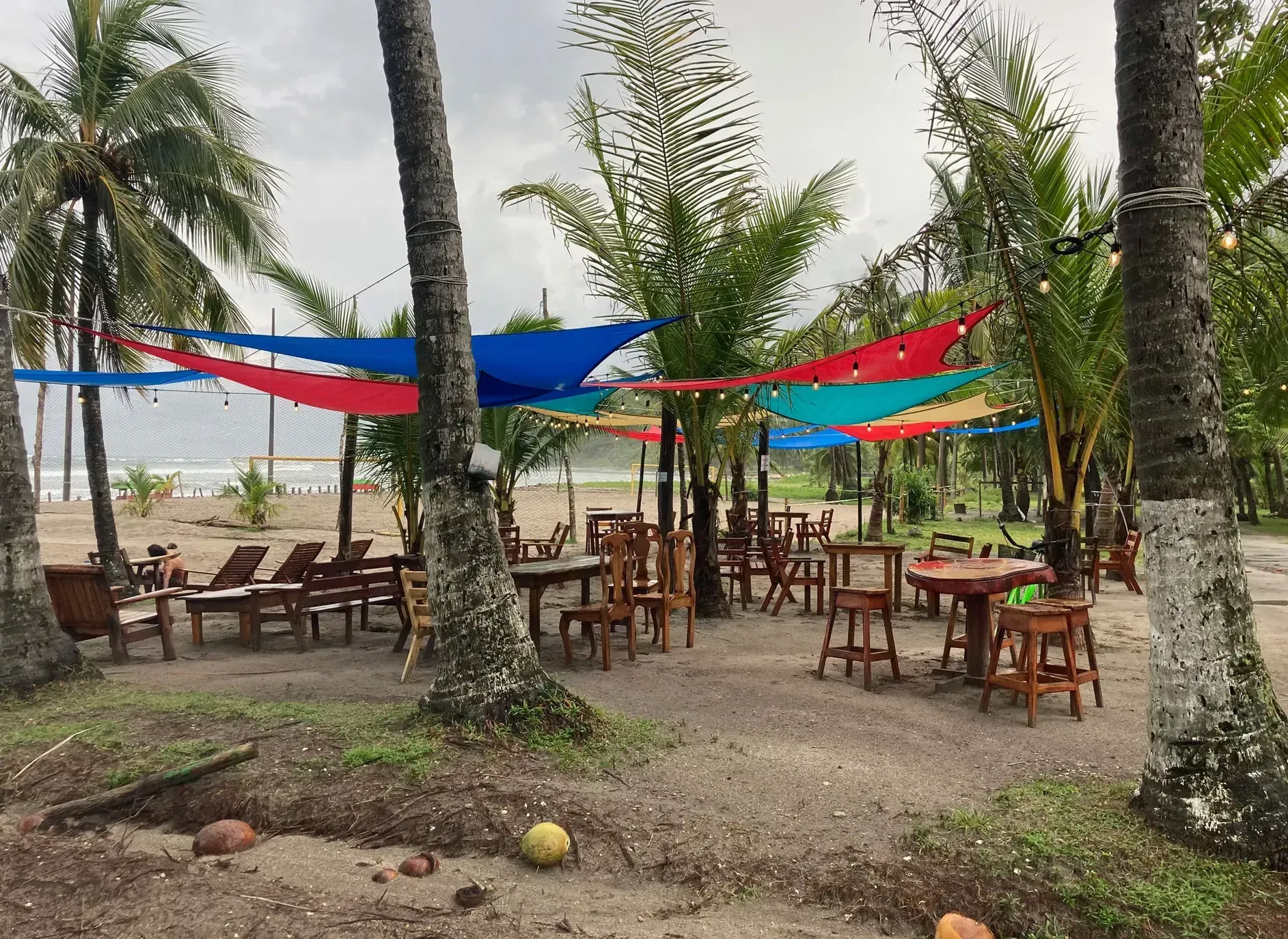 A restaurant on the beach with tables and chairs and umbrellas.