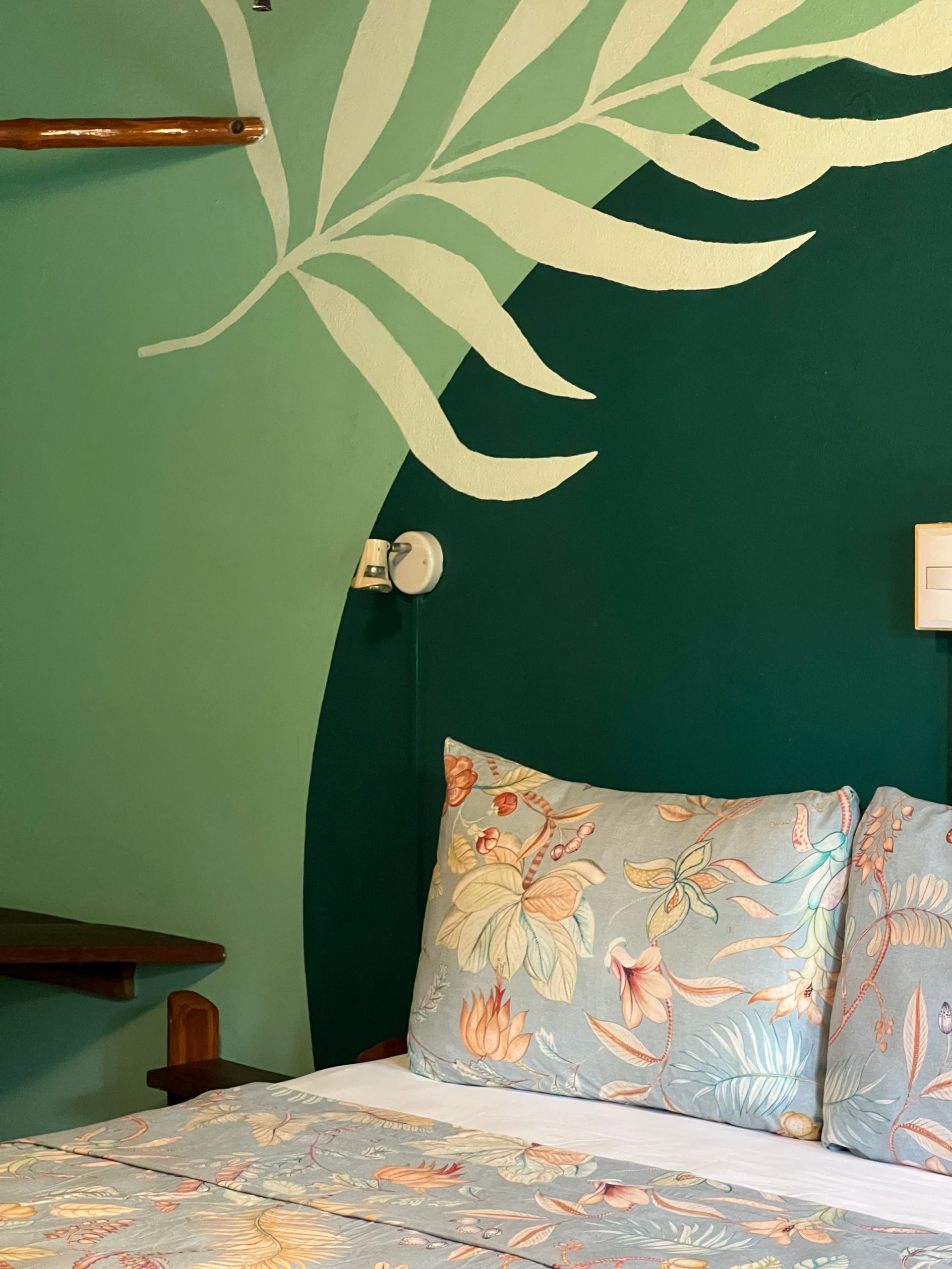 A bed with a leaf painted on the wall behind it
