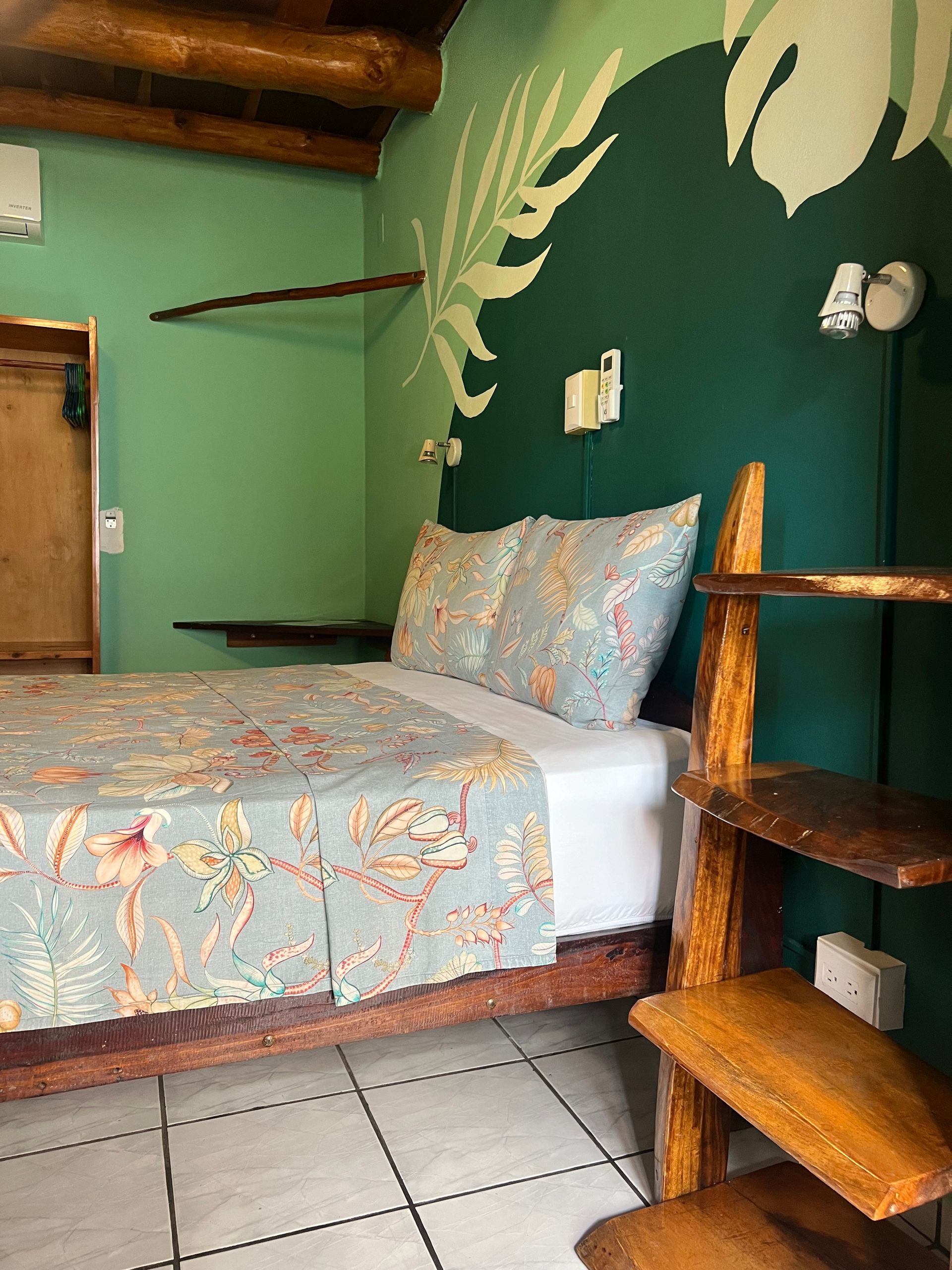 A bedroom with a bed , shelves , and a painting on the wall.