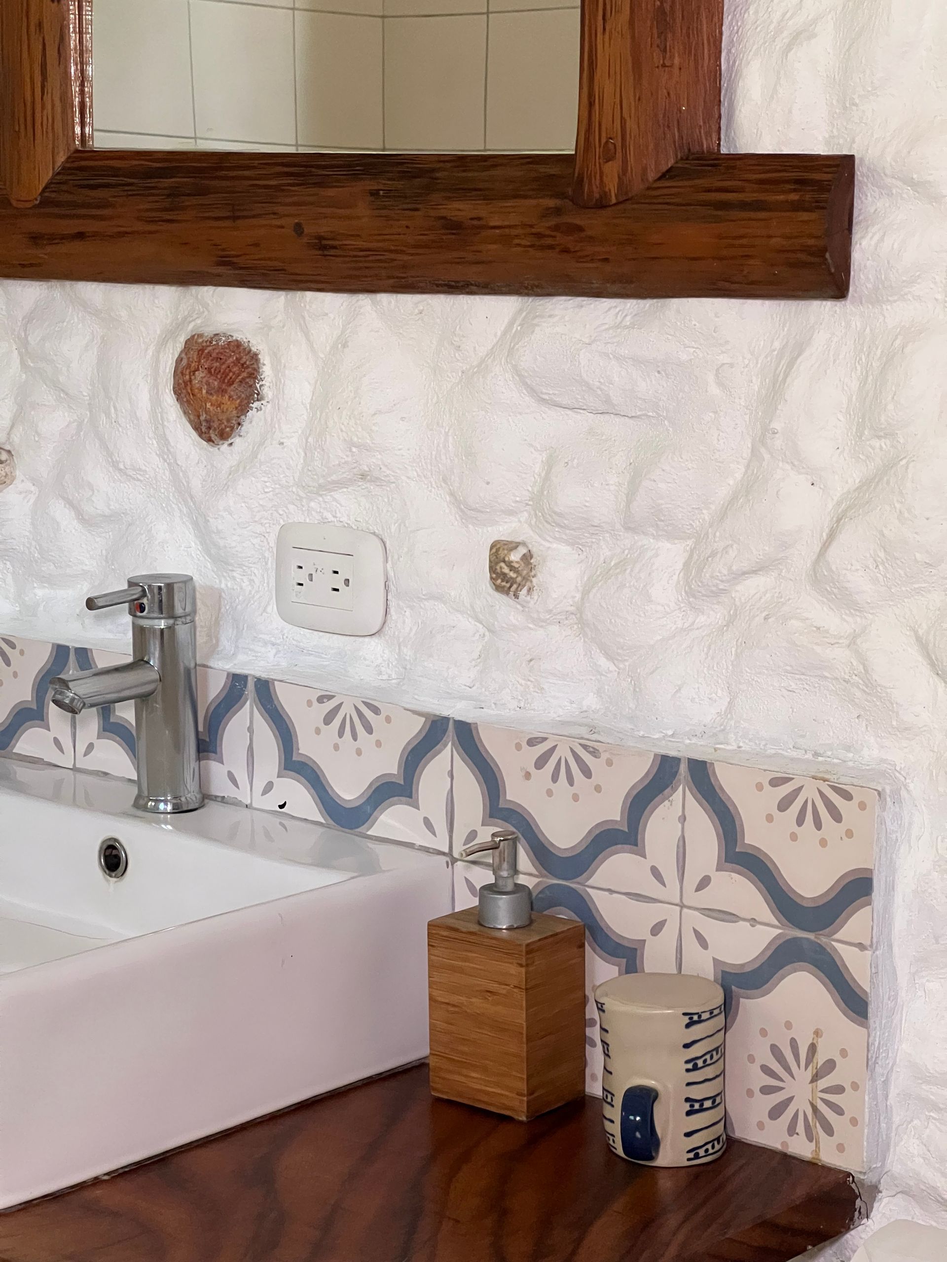 A bathroom with a sink , mirror and soap dispenser