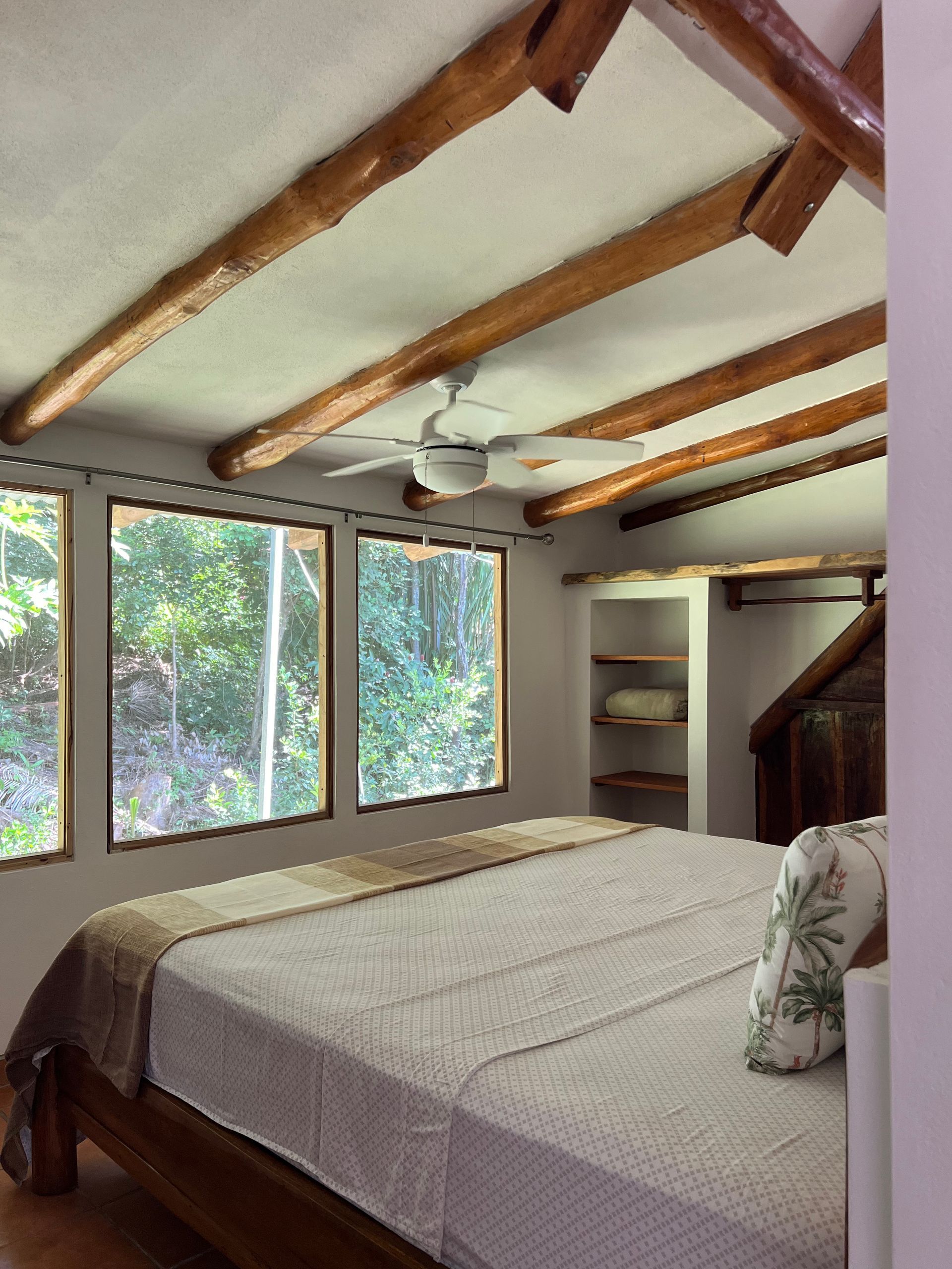A bedroom with a large bed and a ceiling fan