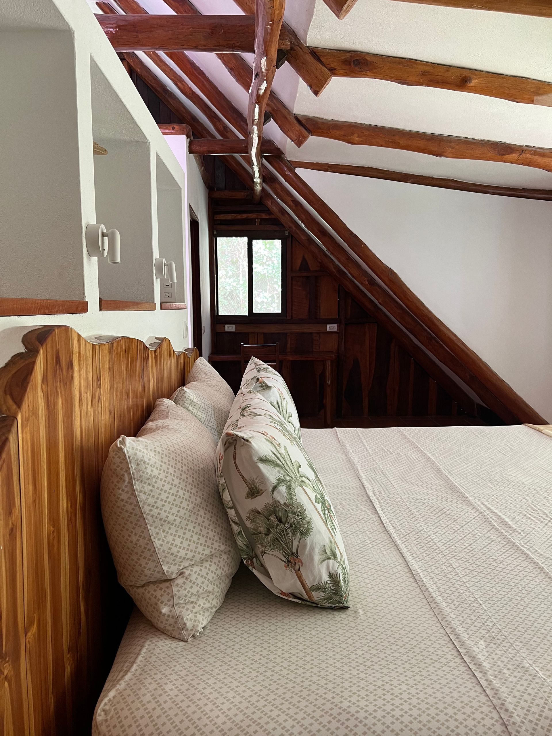 A bed with two pillows on it in a room with a wooden headboard.