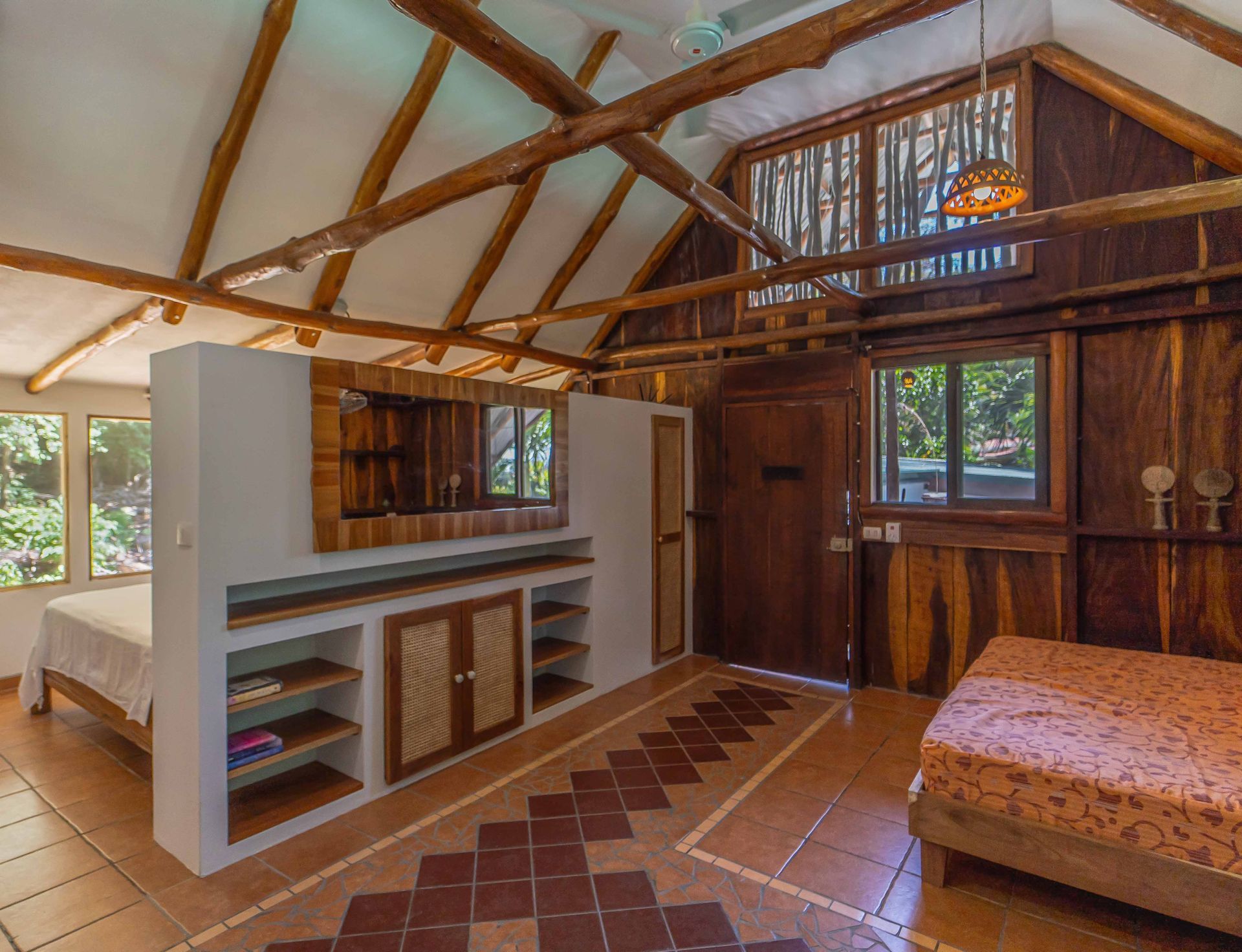 A bedroom in a wooden house with a bed and a dresser.