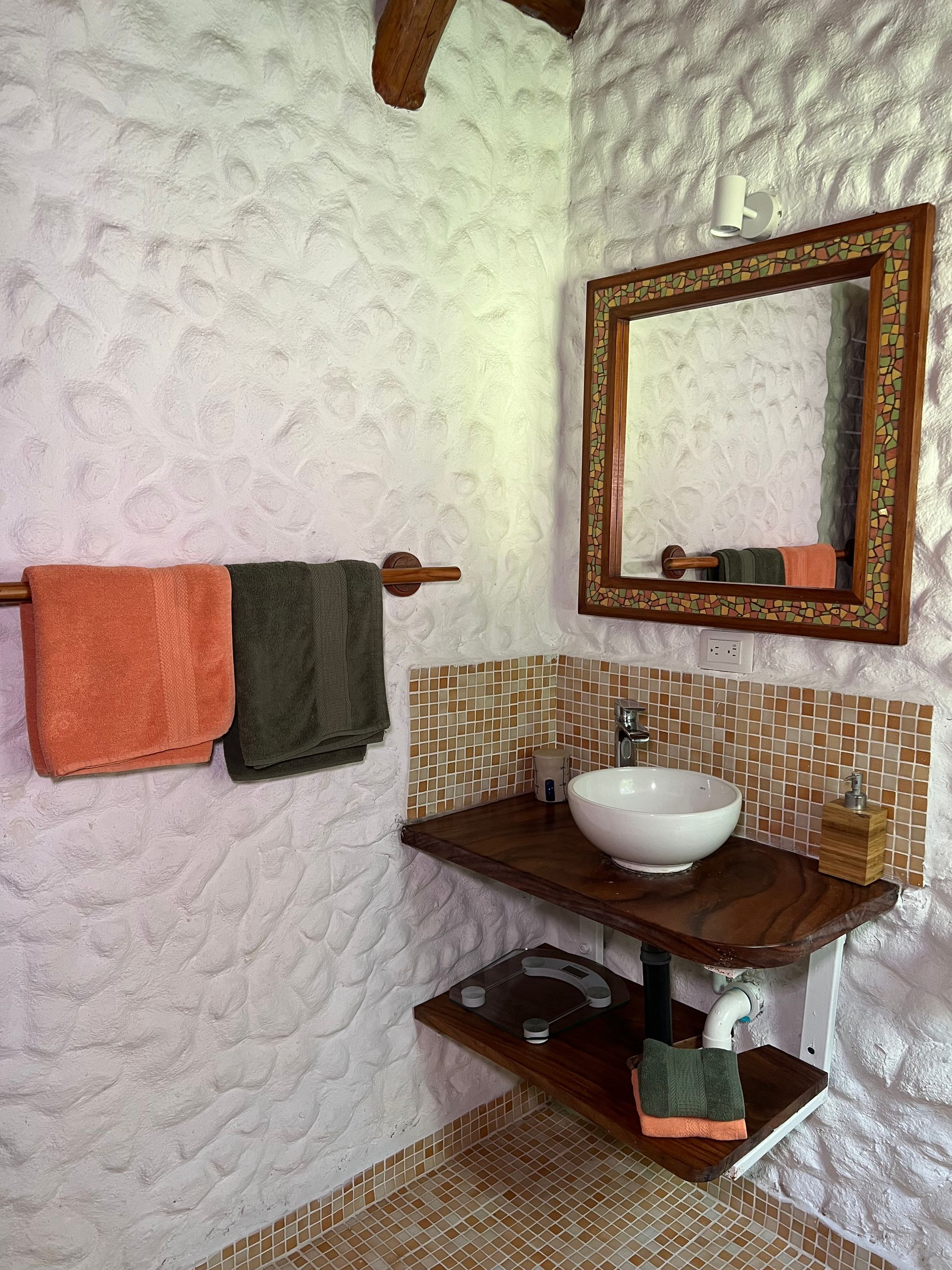 A bathroom with a sink , mirror and towels hanging on the wall.