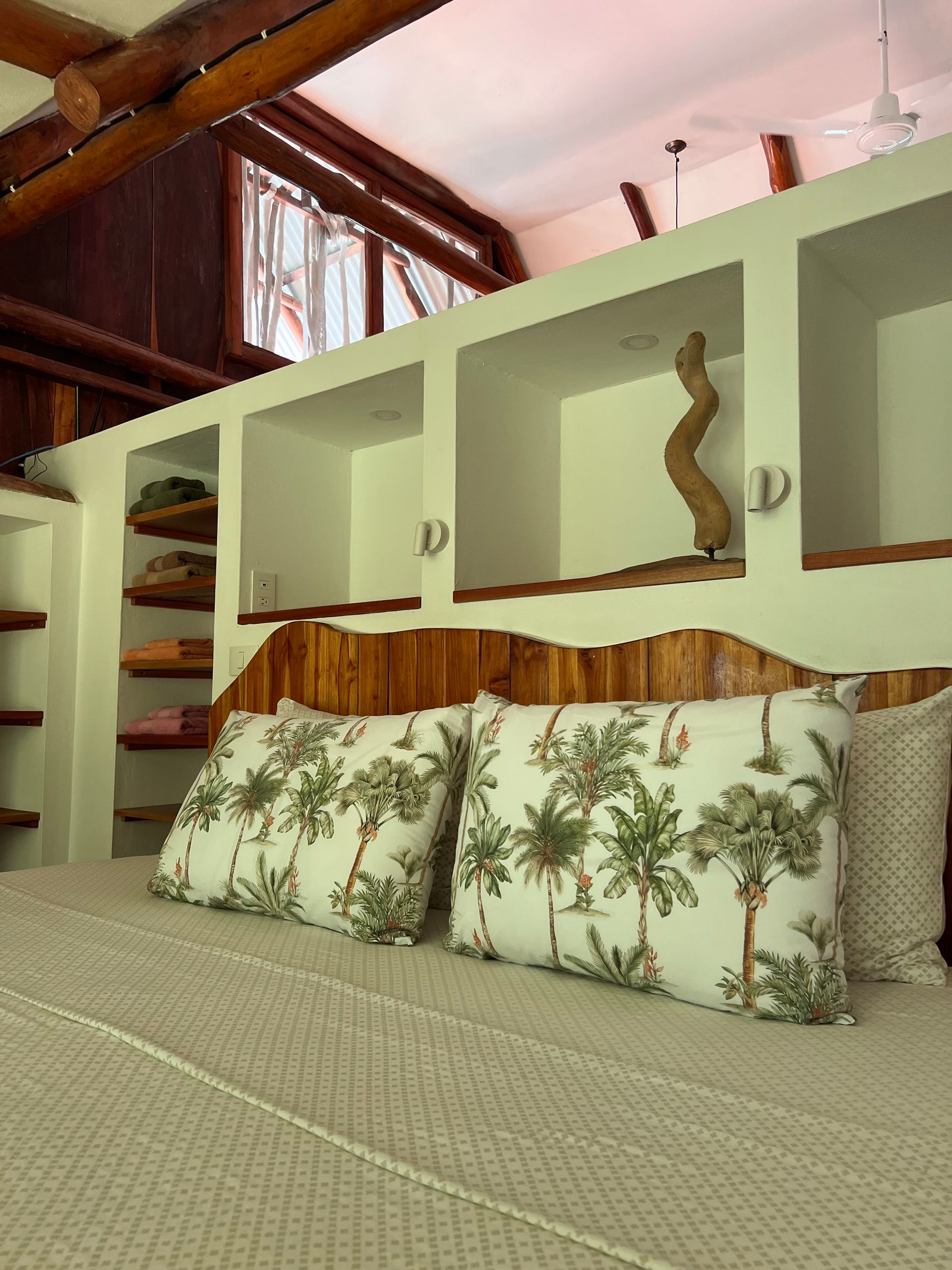 A bed with a wooden headboard and pillows with palm trees on them
