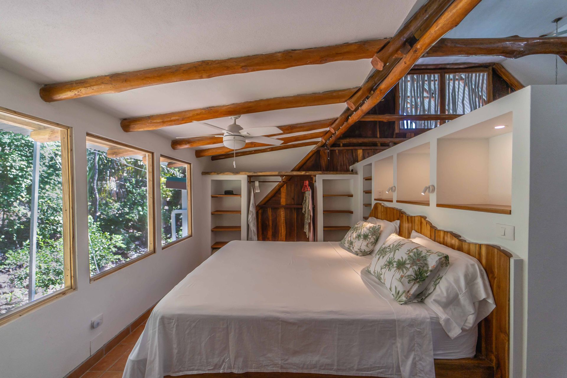 A bedroom with a large bed and lots of windows