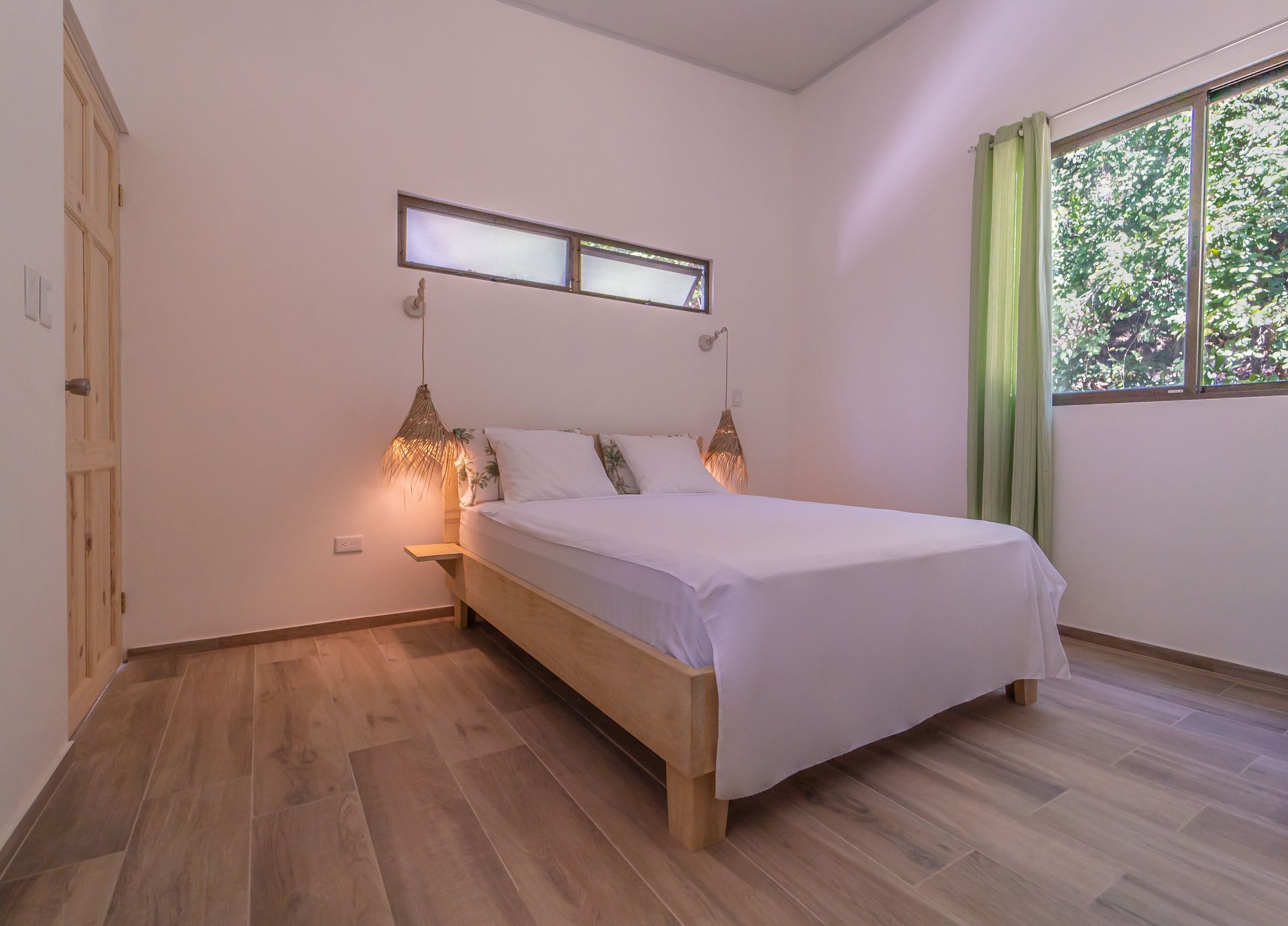 A bedroom with a bed , window and wooden floor.