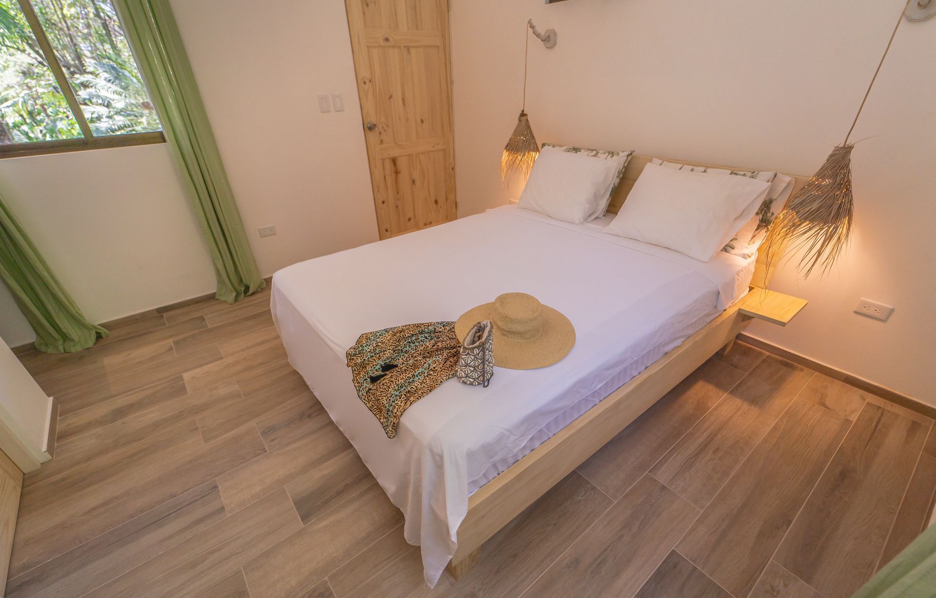 A bedroom with a bed and a straw hat on it.