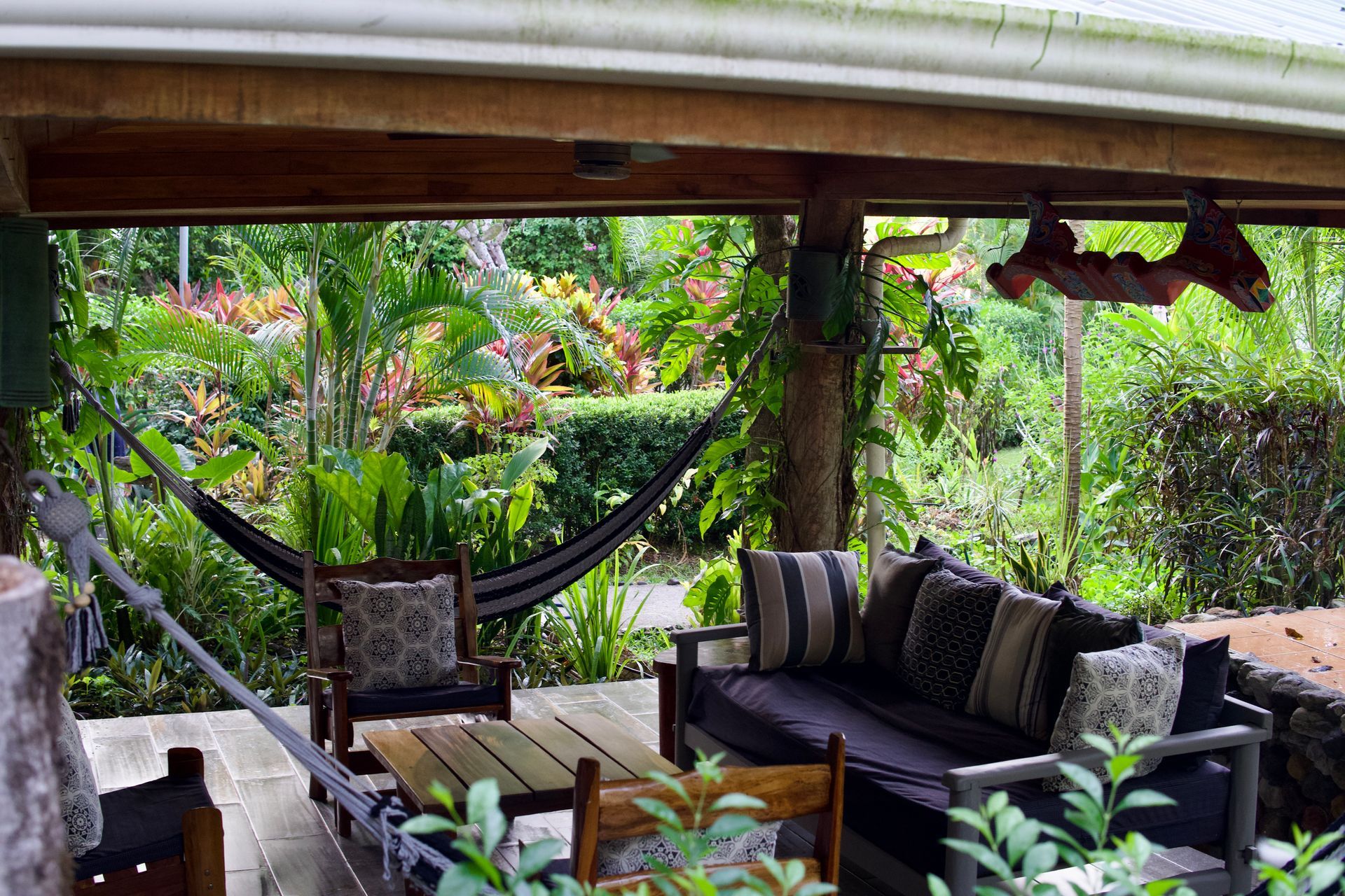 A patio with a couch , chairs , table and hammock.