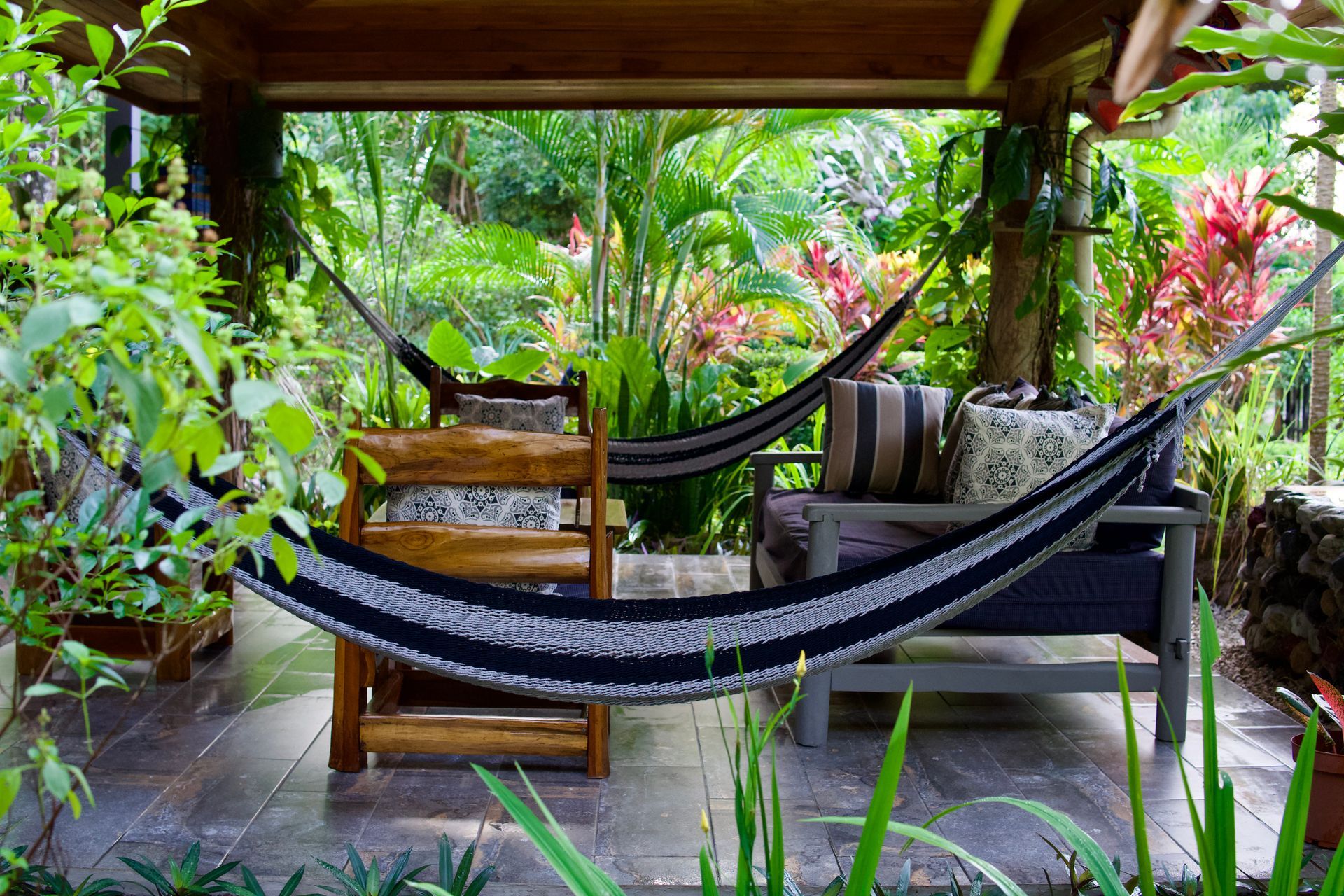 Two hammocks are hanging from a wooden structure in a garden.