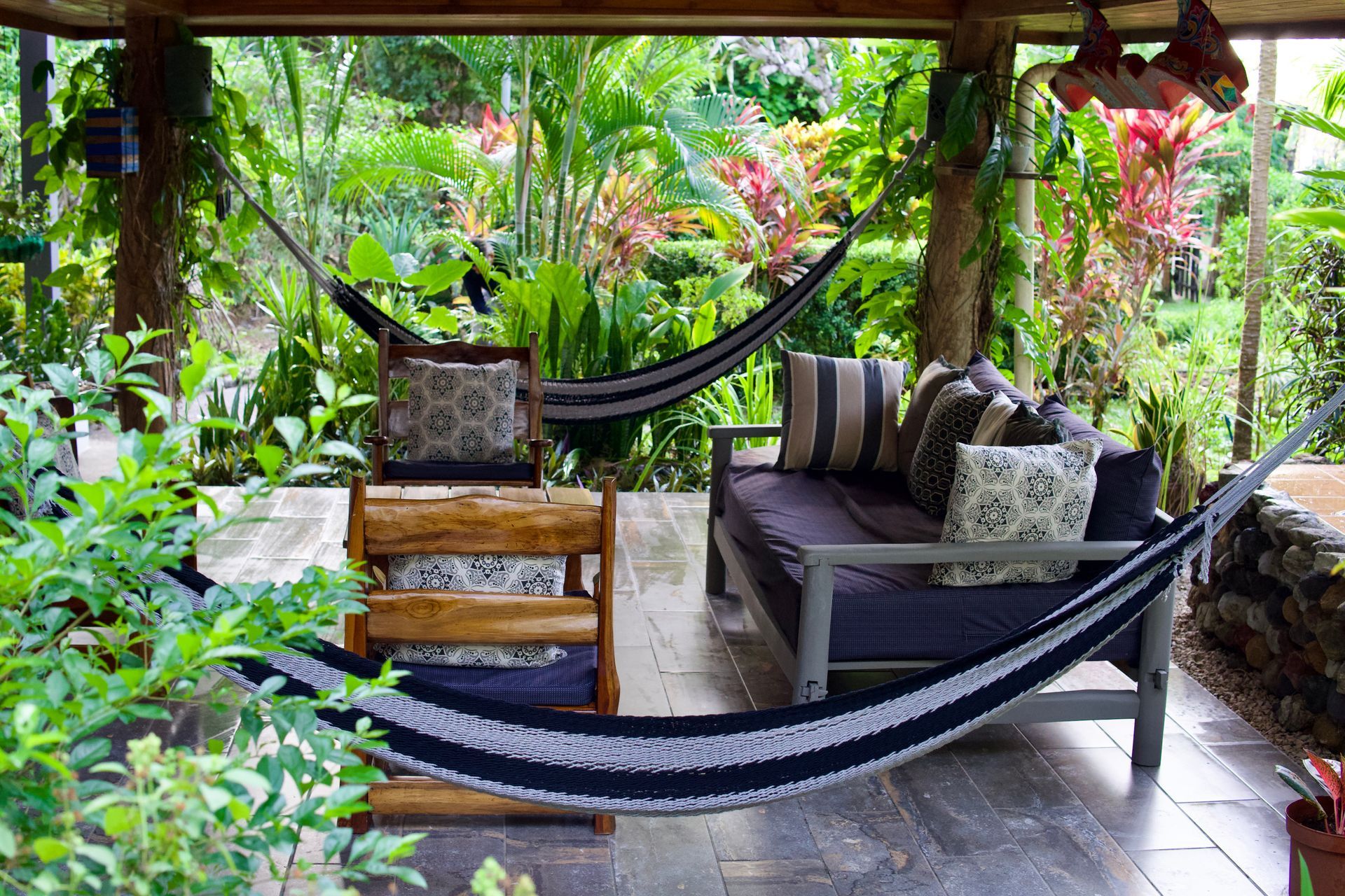 A patio with a couch and chairs and two hammocks