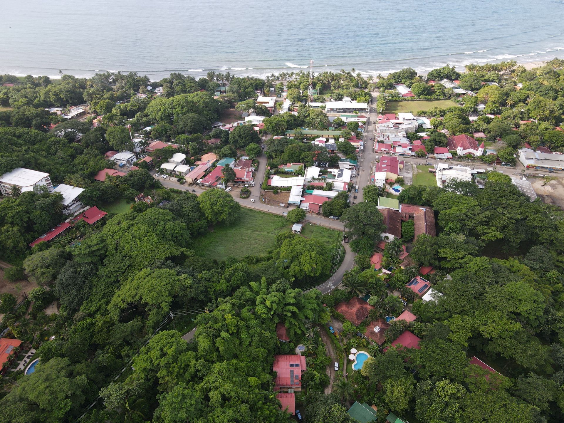 An aerial view of a small town surrounded by trees and houses near the ocean.
