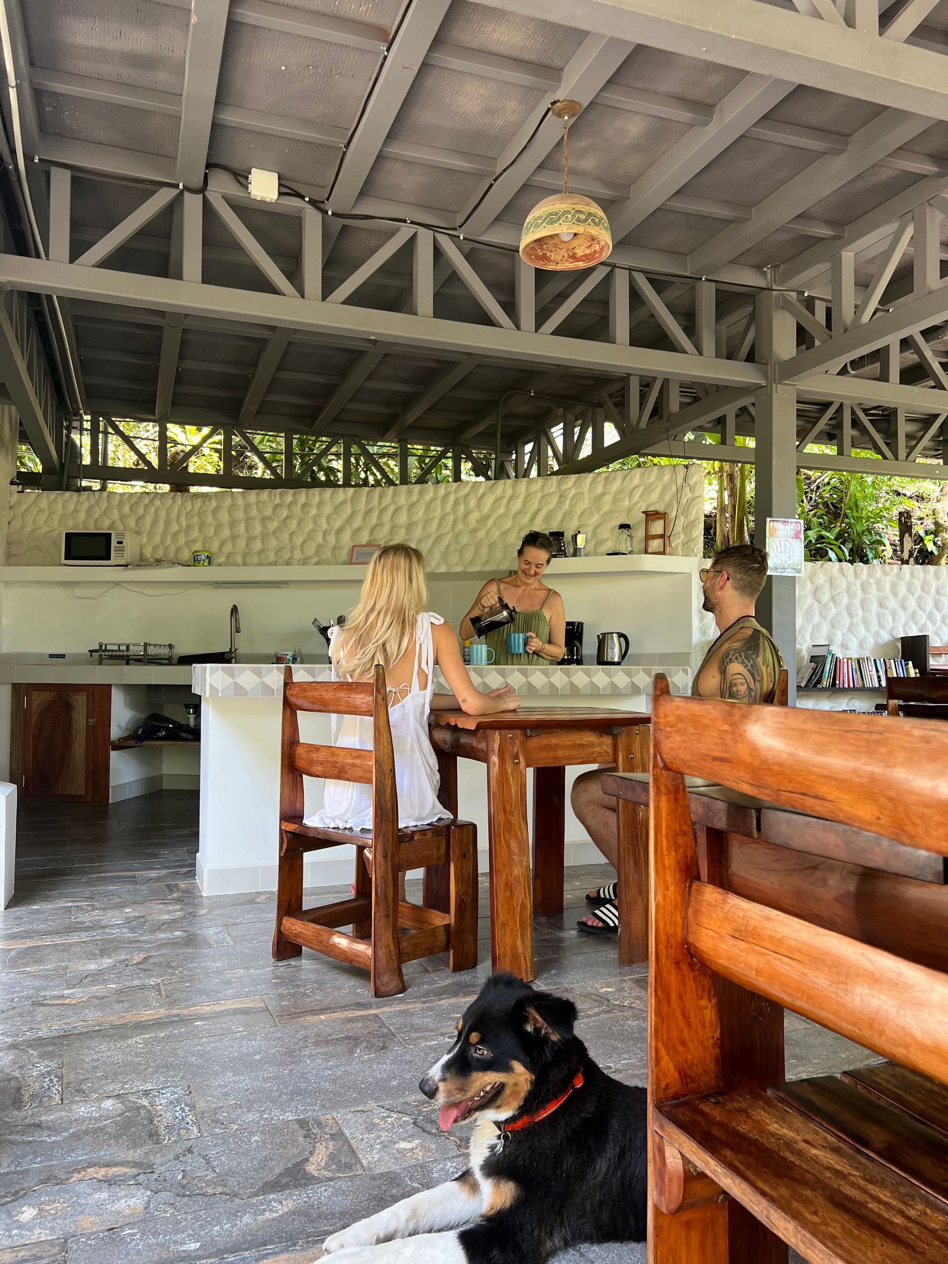 A man and a woman are sitting at a table in a restaurant with a dog laying on the floor.